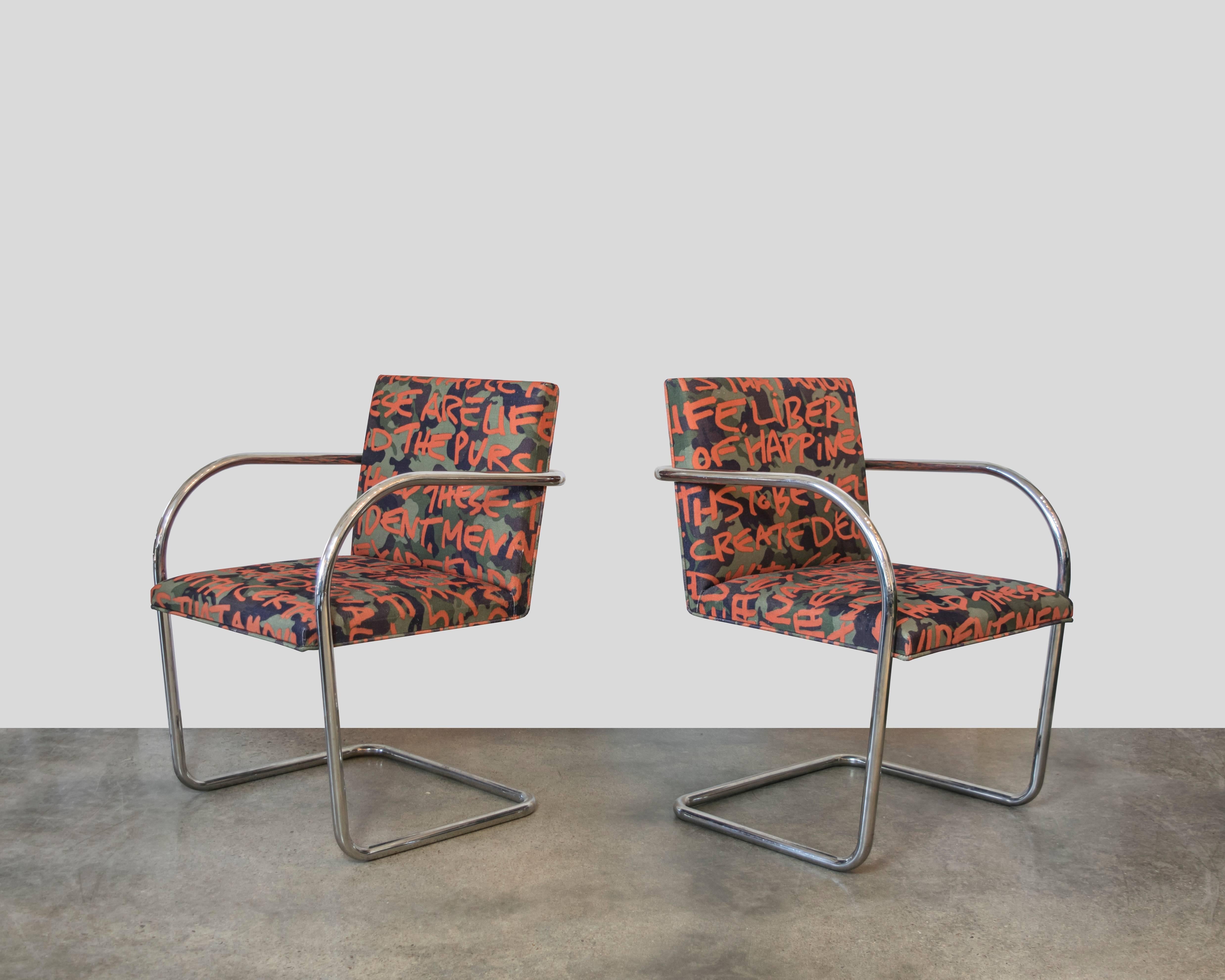 A fun set of Brno tubular chairs in custom Karl Lagerfeld fabric. The upholstery is an abstract of the Declaration of Independence. The fabric has a background of camouflage with bright orange lettering making these a standout piece and perfect for