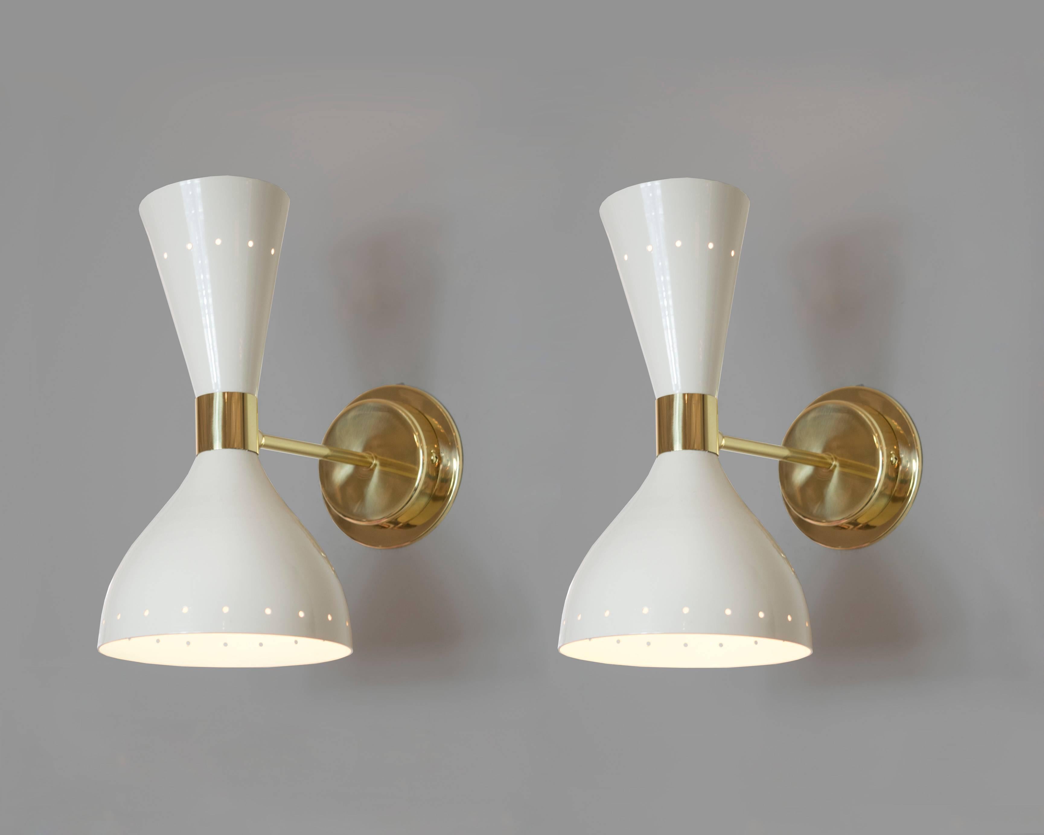A pair of Stilnovo white lacquer and brass sconces with both up and down lighting in a conical shape. The outer rim extends 11.5 inches from the wall and the upper cone has a ring of perforated circles to add more drama to the pair. 