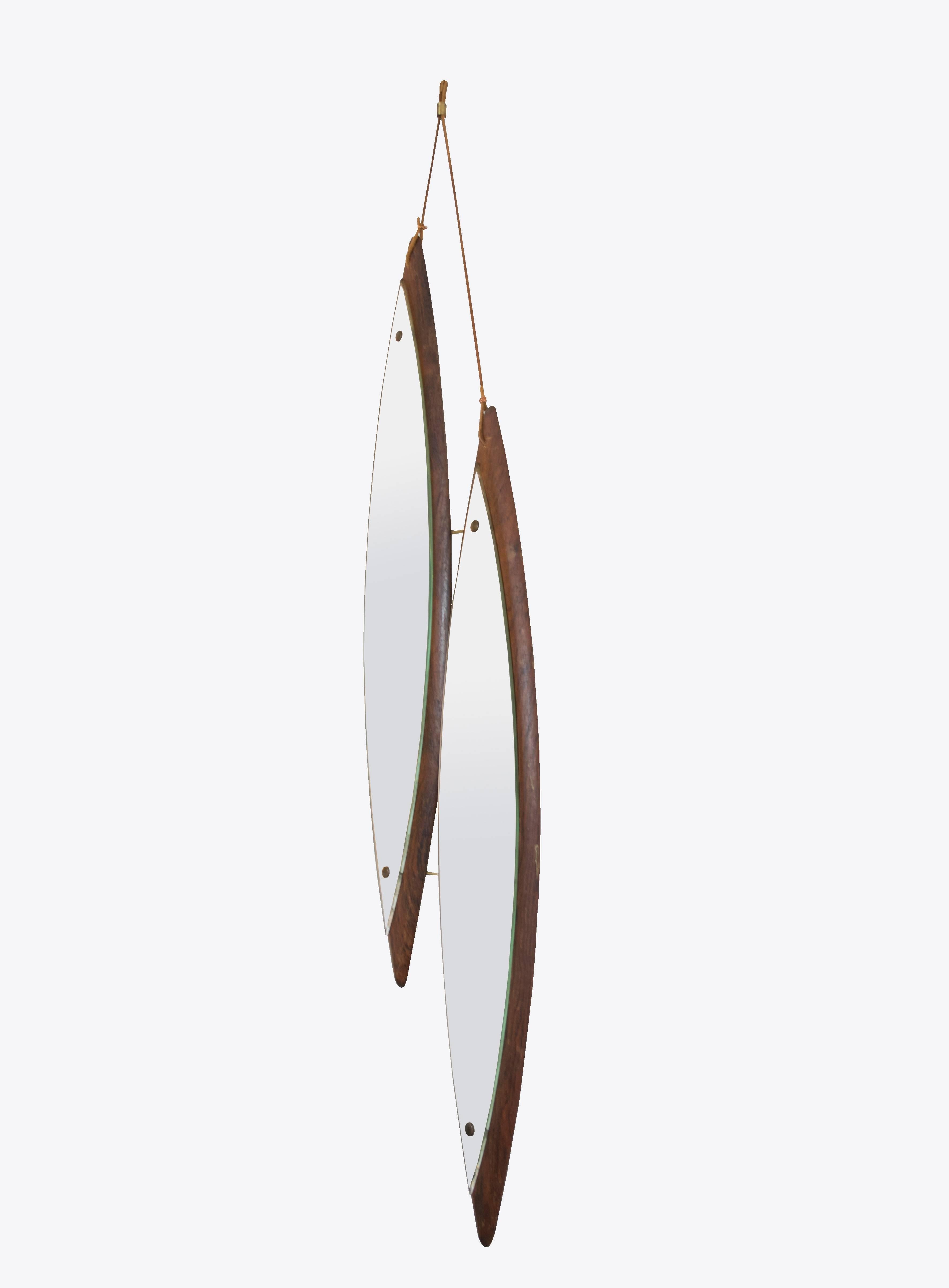 This is a highly unusual design, asymmetrical diamond shaped rosewood mirrors fastened together by brass rods and hanging by double leather straps with a brass clasp.