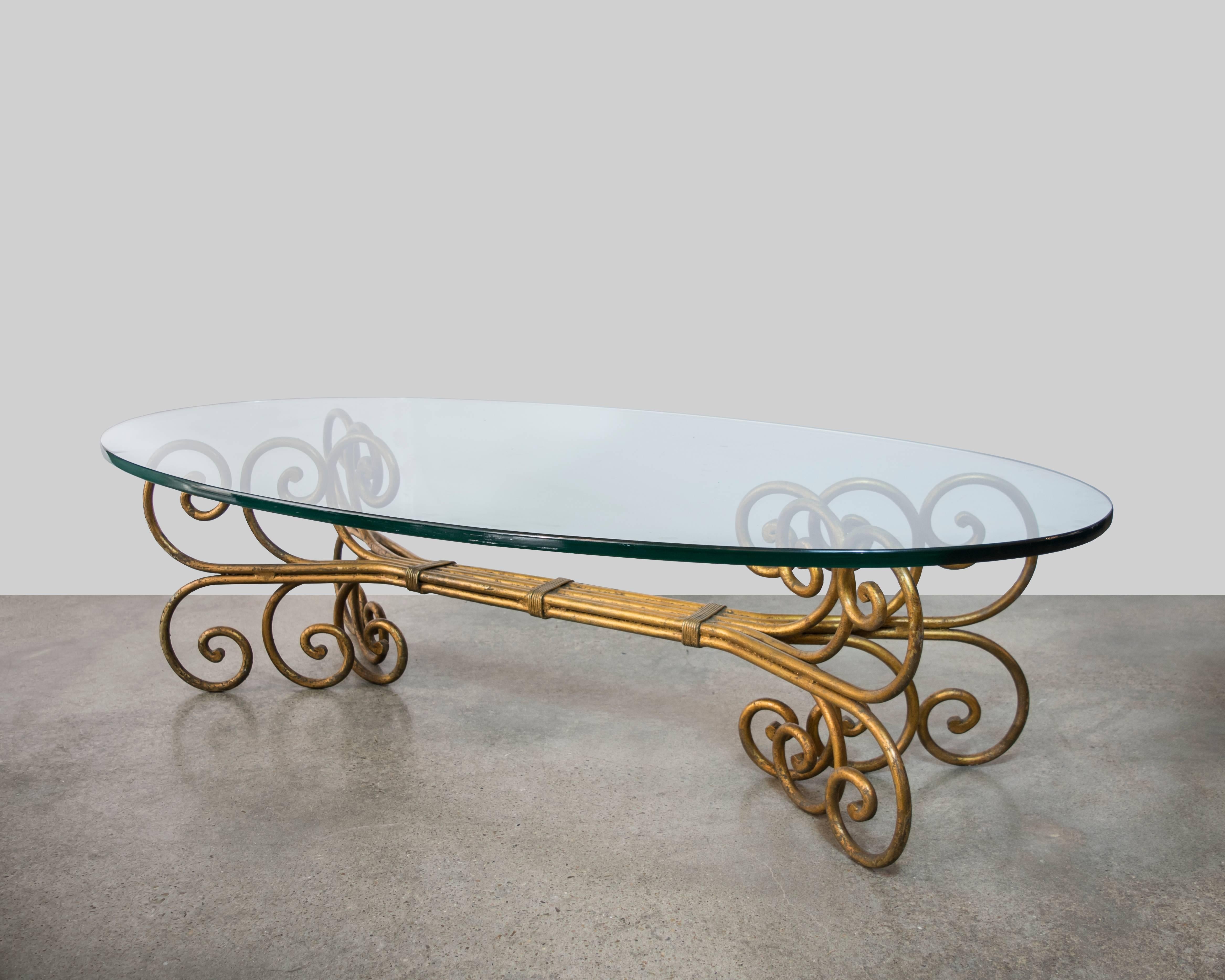 This is a very elegant and highly stylized Hollywood Regency oval shaped coffee table with intricate scroll design.