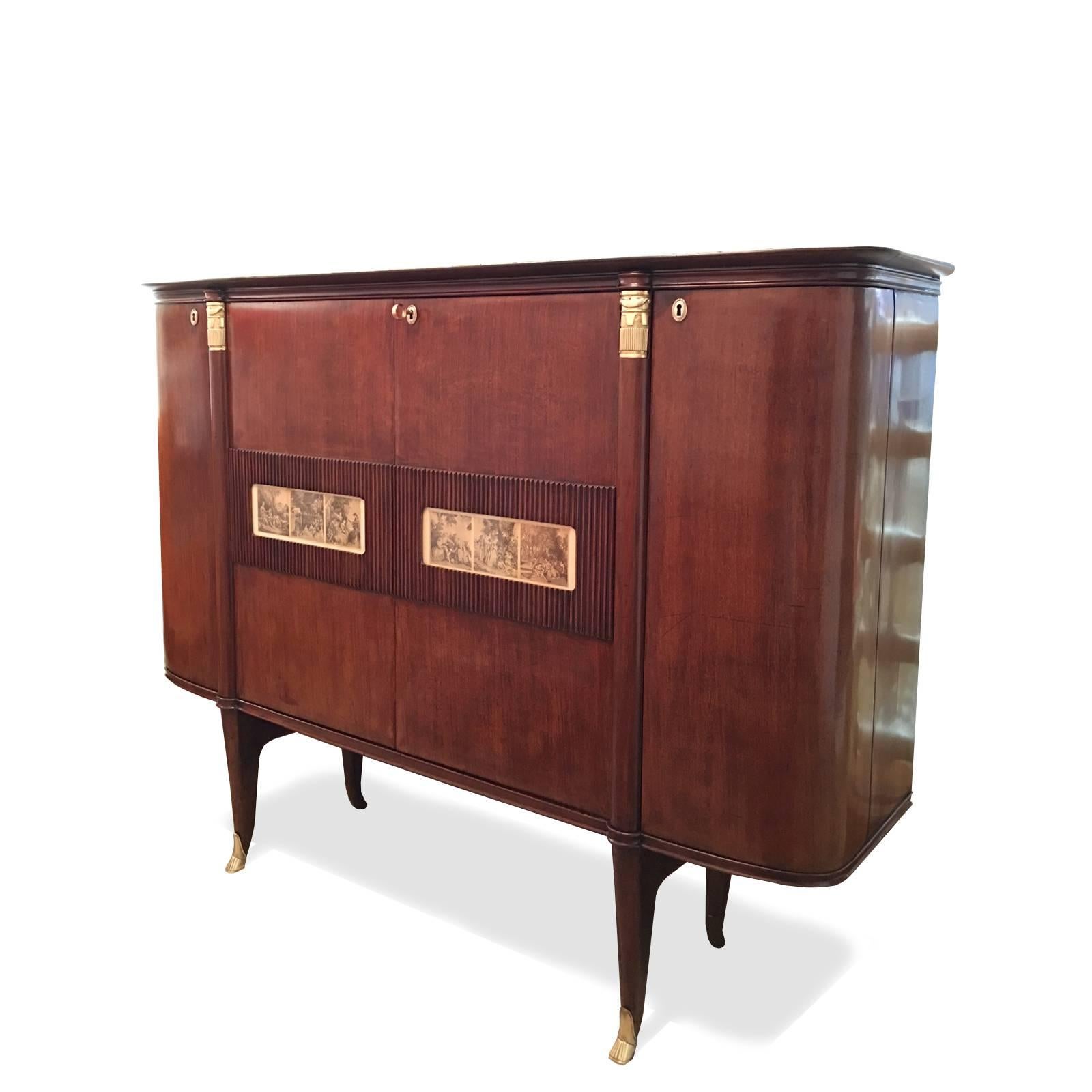 This very elegant bar cabinet has two tall side curved doors with shelves behind and a main central compartment composed by two engraved mahogany doors embellished by bronze mounts and 18th century lithographs of classical scenes. The interior is
