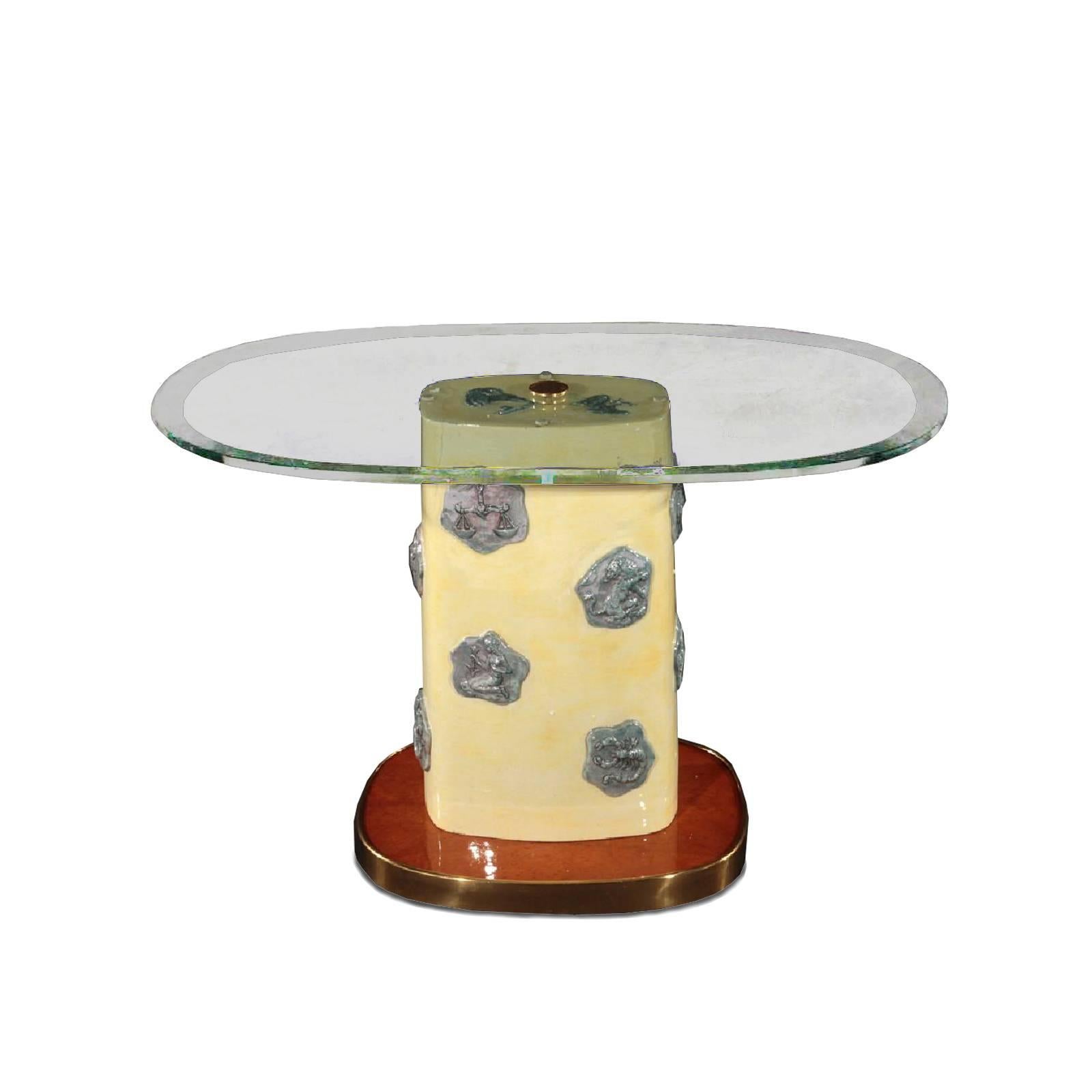 A stunning and unique 1960 Italian side table with glass oval top, glazed ceramic base with zodiac signs motif, raised on brass trimmed base.

 