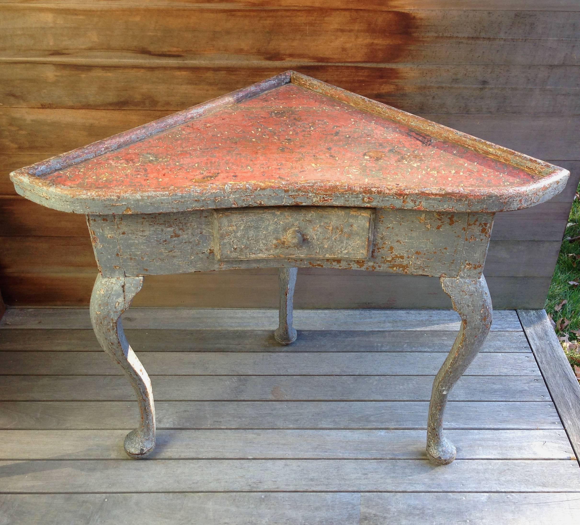 A 19th century Swedish Gustavian corner table with a raised banded edge, exhibiting a slight concave front with single drawer supported by three cabriole legs terminating in pad feet. Original painted surface.