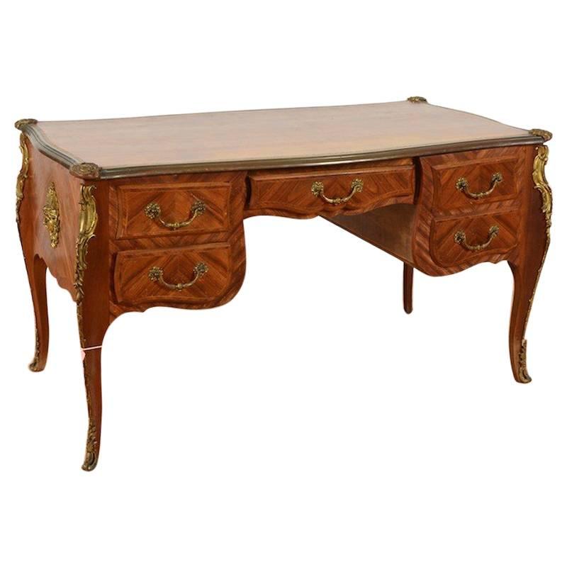 A kingwood veneered bureau plat in Louis XV taste with bronze ormolu and inset embossed leather top. Five drawers on one side with five false draw fronts on the other.