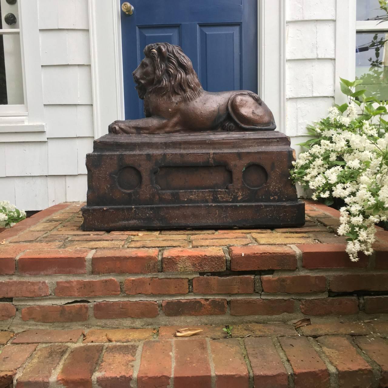 A 19th century English salt glazed stoneware recumbent lion, raised on plinth.