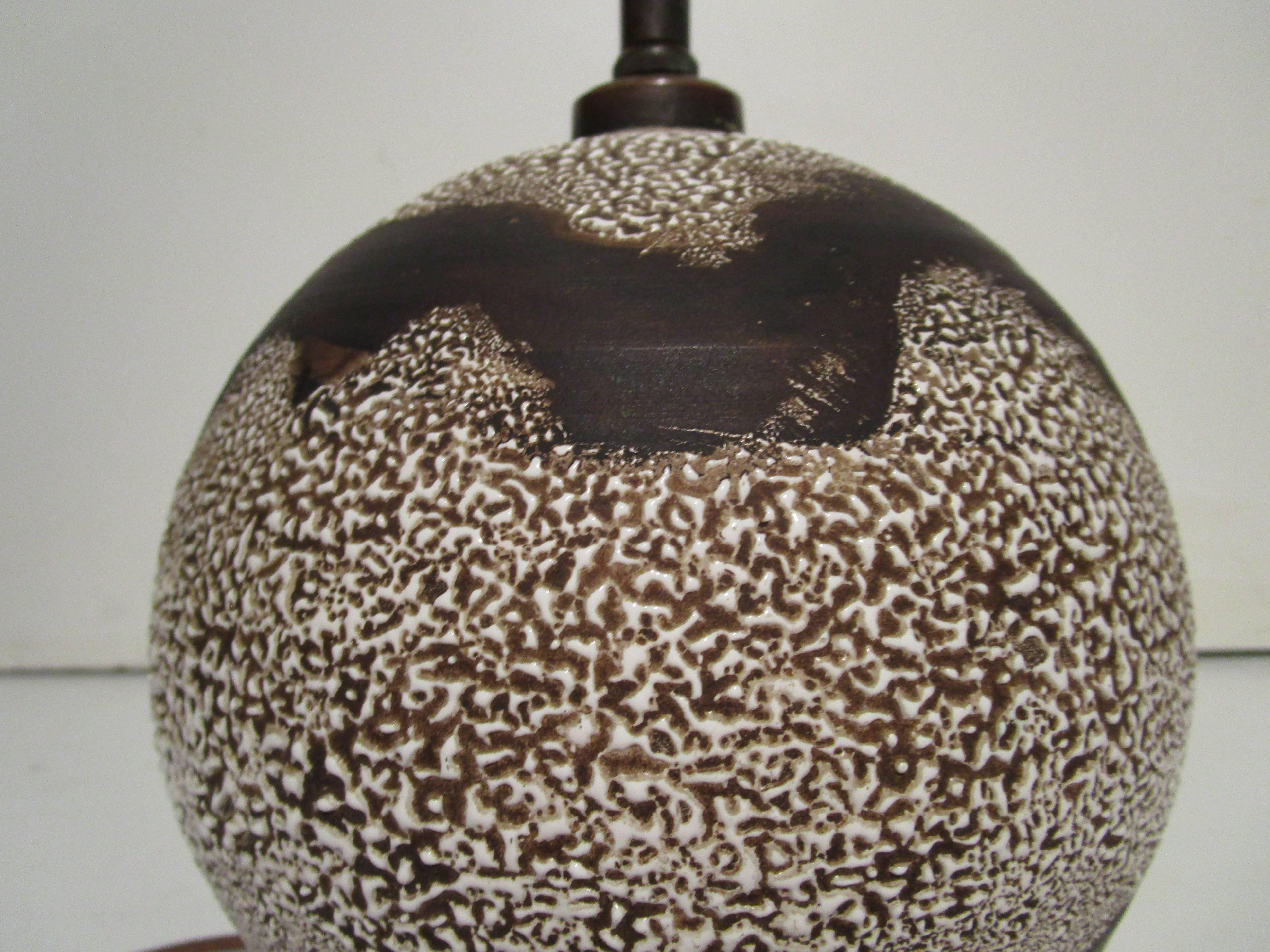 Table lamp in the style of Jean Besnard. Brown glazed spherical form stoneware with two bands of ivory textured glaze. Newly rewired with brown silk cord.

Dimensions: 8