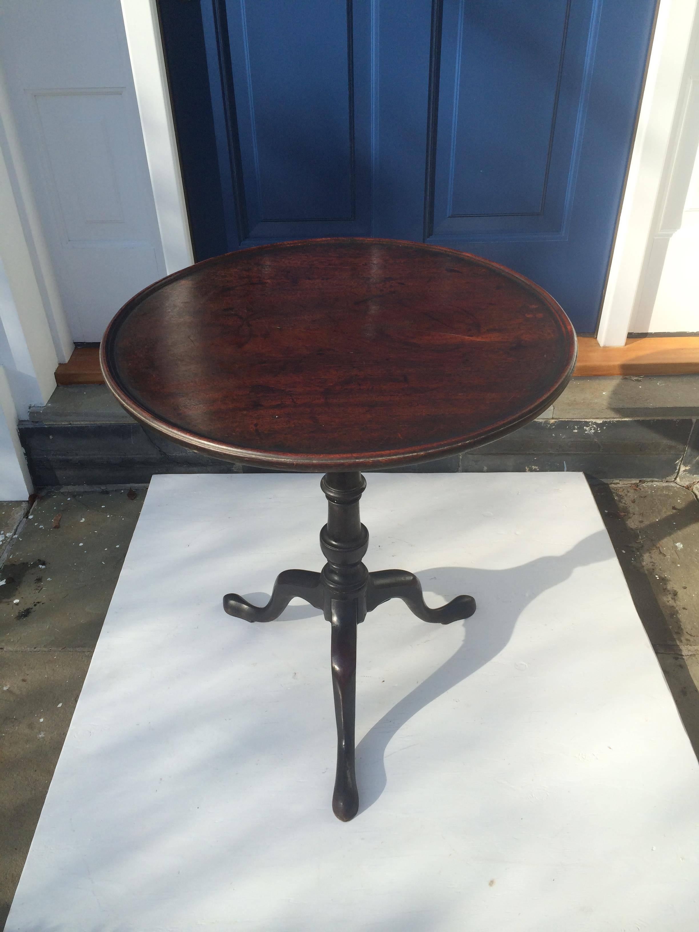 George III mahogany tilt-top table, England, 18th century. Circular rimmed tilting top above turned column and tripod base with pad feet.

 
