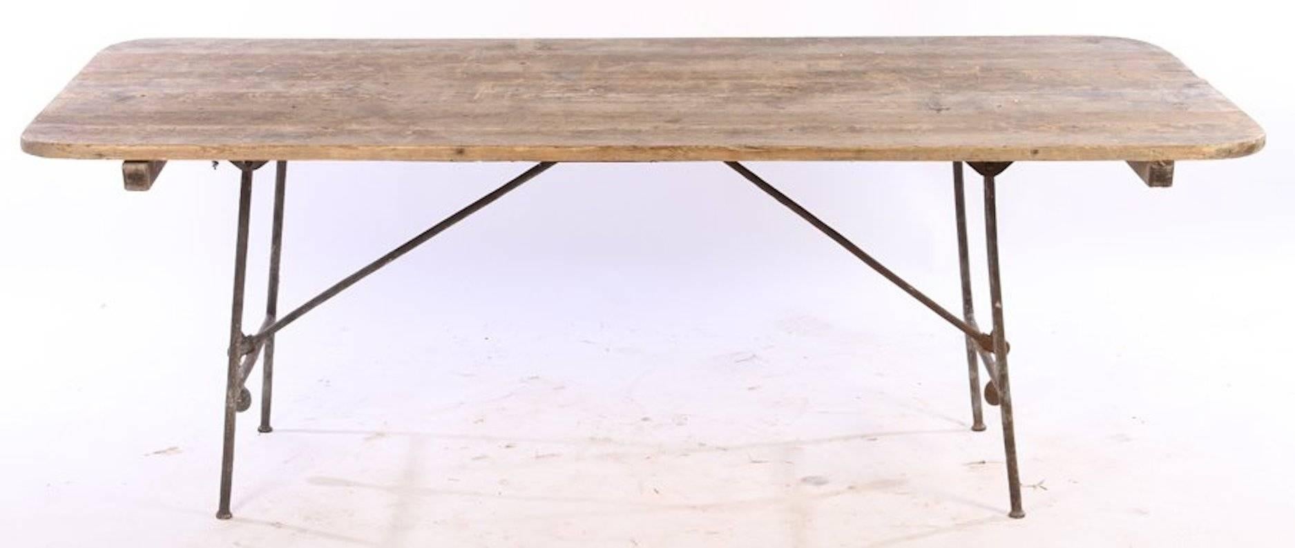 Wood plank tabletop with iron folding legs and counterbalance weights, Continental, early 20th century. 

Dimensions: 28" H x 79" W x 38" D.