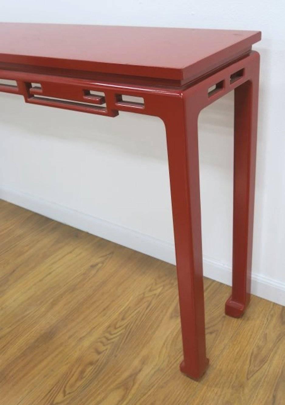 American Mid-Century Modern Asian Style console. Carved fretwork apron above solid legs that end in an upturned horse hoof foot, all professionally lacquered red. 
