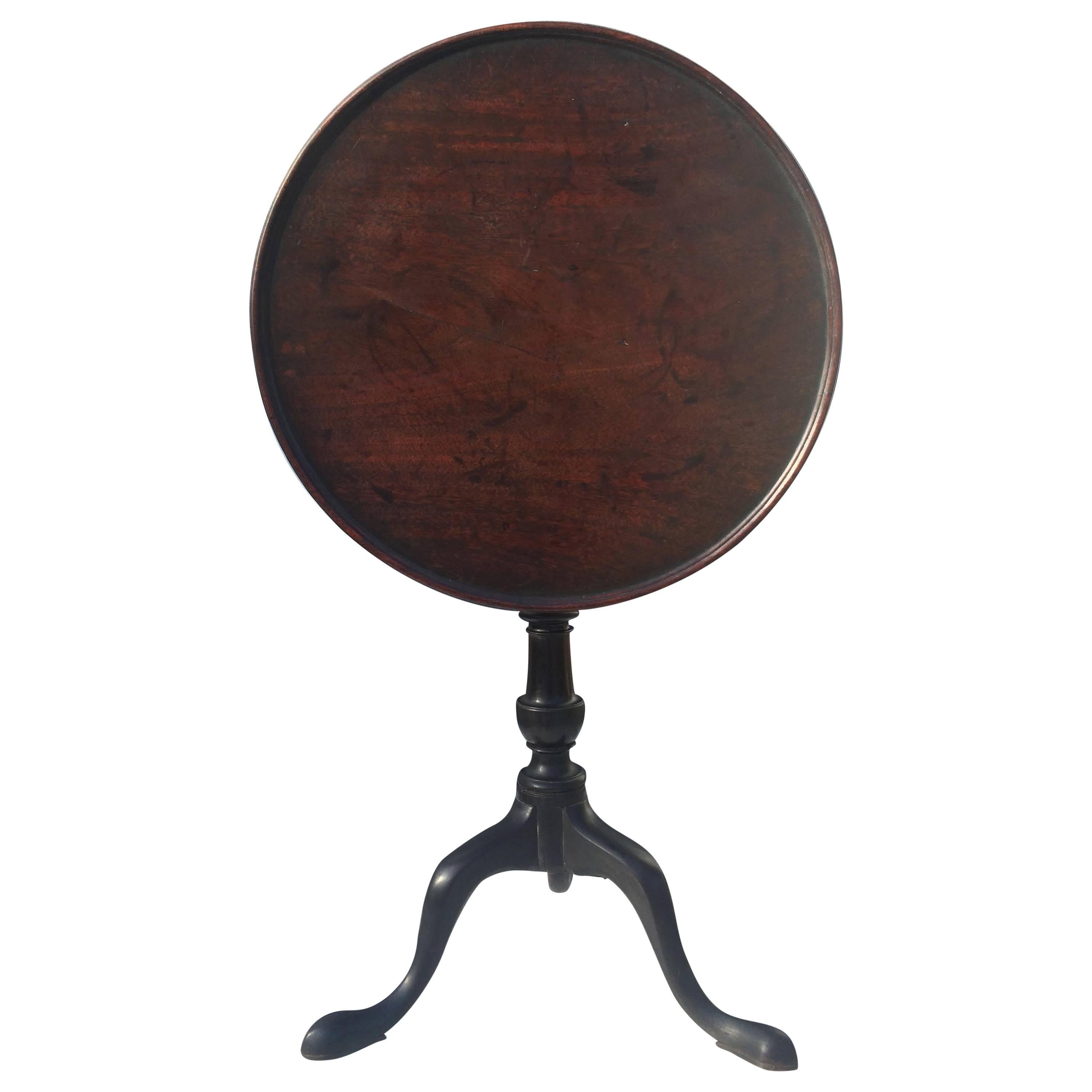 George III mahogany tilt-top table, England, 18th century. Circular rimmed tilting top above turned column and tripod base with pad feet.
 
        