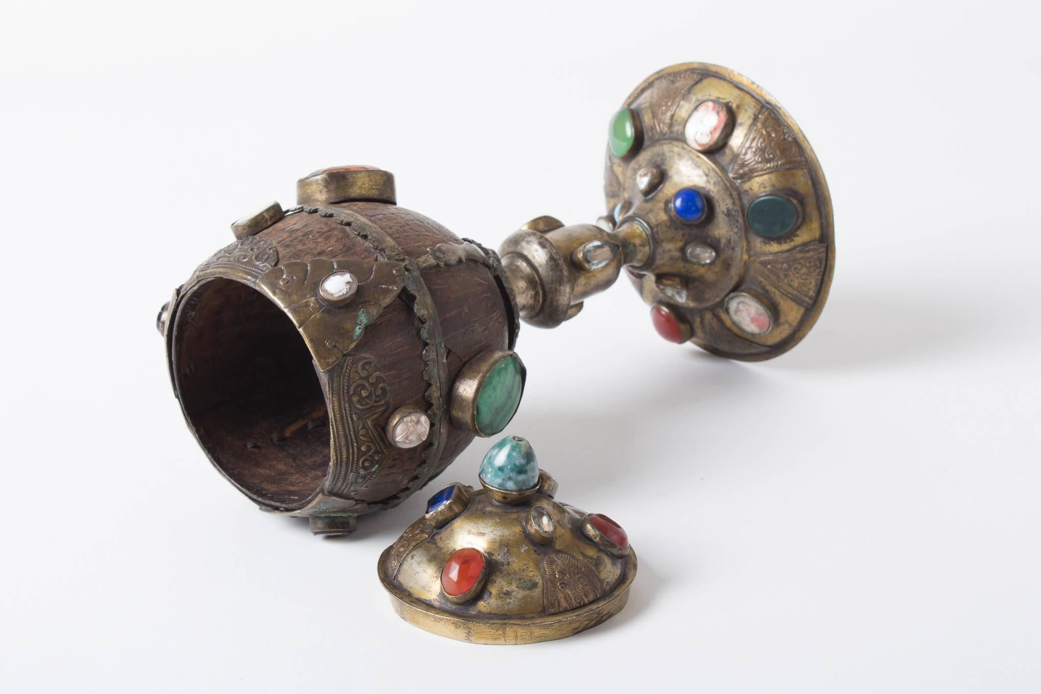 A Coconut Cup, with numerous mounted semi-precious stones like 

carnelian, rock crystal malachite, colorless topaz, aquamarine, lapis lazuli, further 3 beautiful baroque water pearls, 2 glass stones , 3 gems or cameos, 2 micro-mosaics with semi-