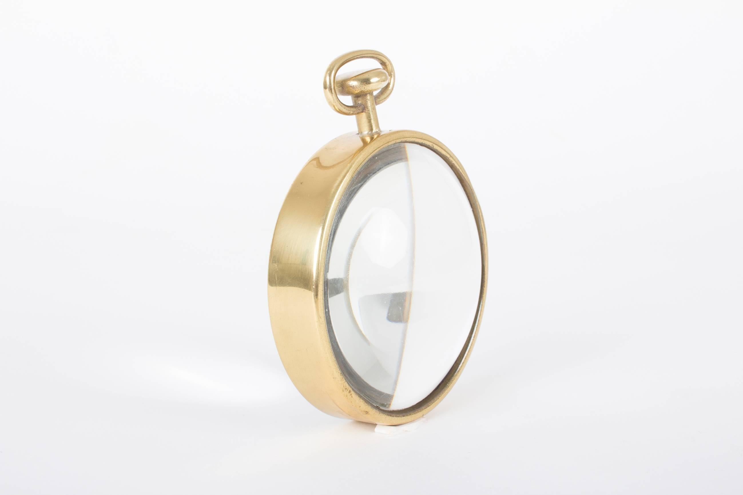 Another fine example of the humorous design by Carl Auböck.
The lens is shaped in the form of a pocket watch and served as a desk accessory. The glass of this magnifier lens seems to be in fine condition, the brass mount has to