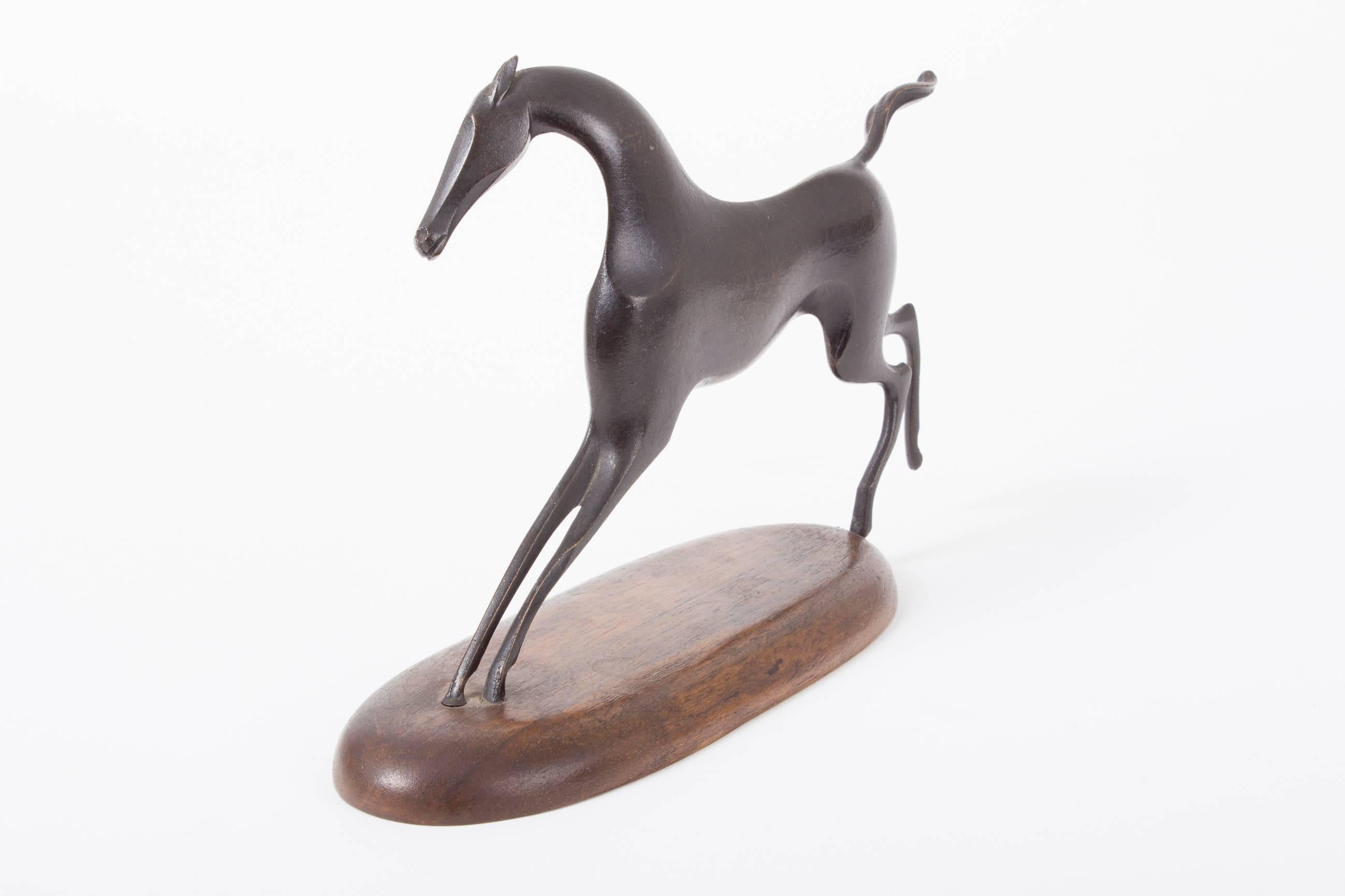 A perfect example of the Hagenauer workshops sculptural works.
The sculptural shape is made from patinated and solid brass.

Mounted only the front hoofs, the way to fixate the horse on the oval wooden  base underlines the elegant character of