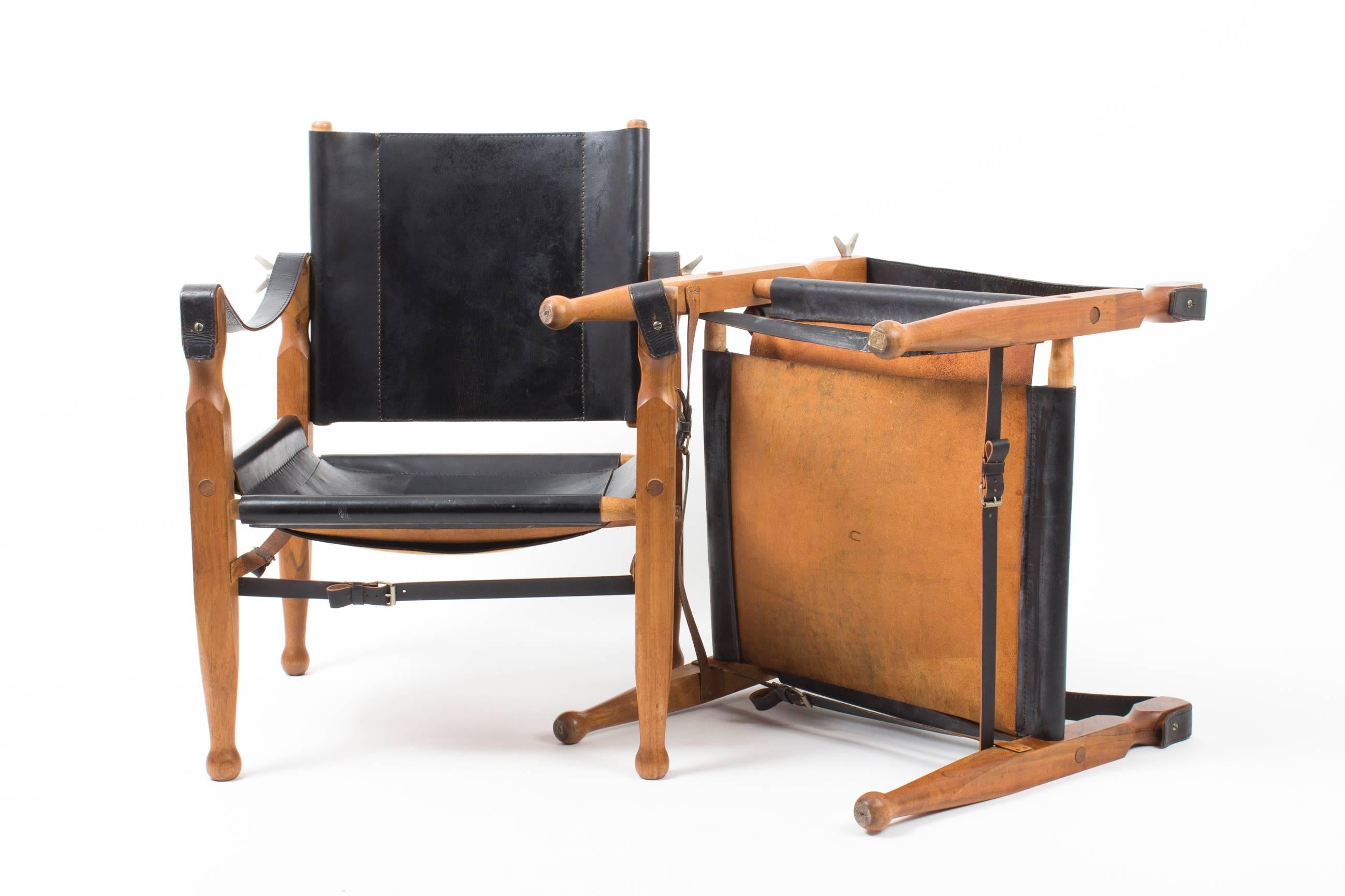 A pair of well known and sought after Auböck safari chairs in mint condition.
Pivoting backrest, wrap strap and arm strap fastened with brass belt buckle detail.

This exceptional pair of safari chairs was restored (strap belt) by the workshop