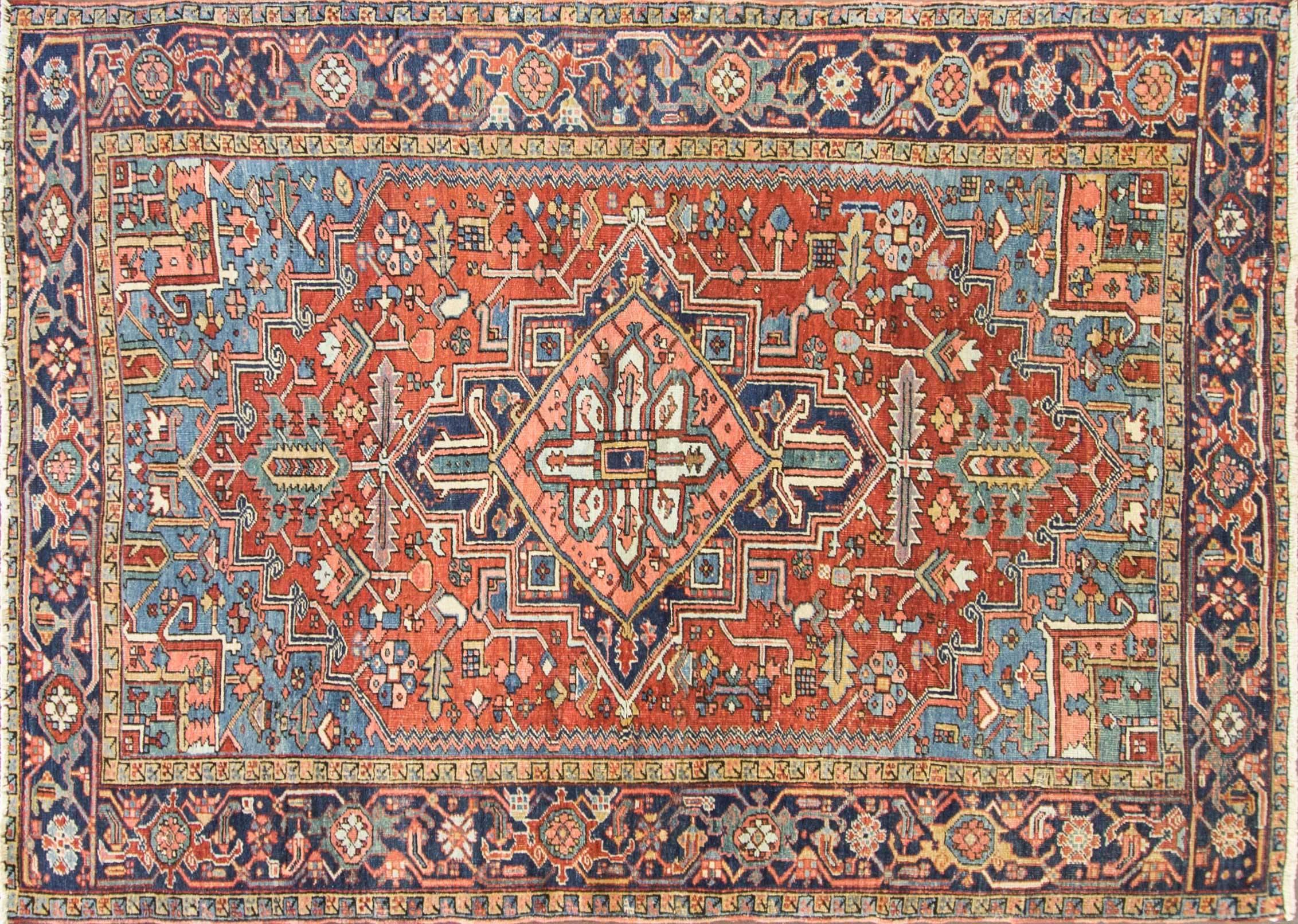 Antique Persian Heriz rug, Persia, circa 1920. This remarkable and artistic antique rug, showcases an ornate, multicolored central design. At the heart of the antique Persian Heriz Serapi rug, a many-petaled flower is surrounded by a 12-pointed