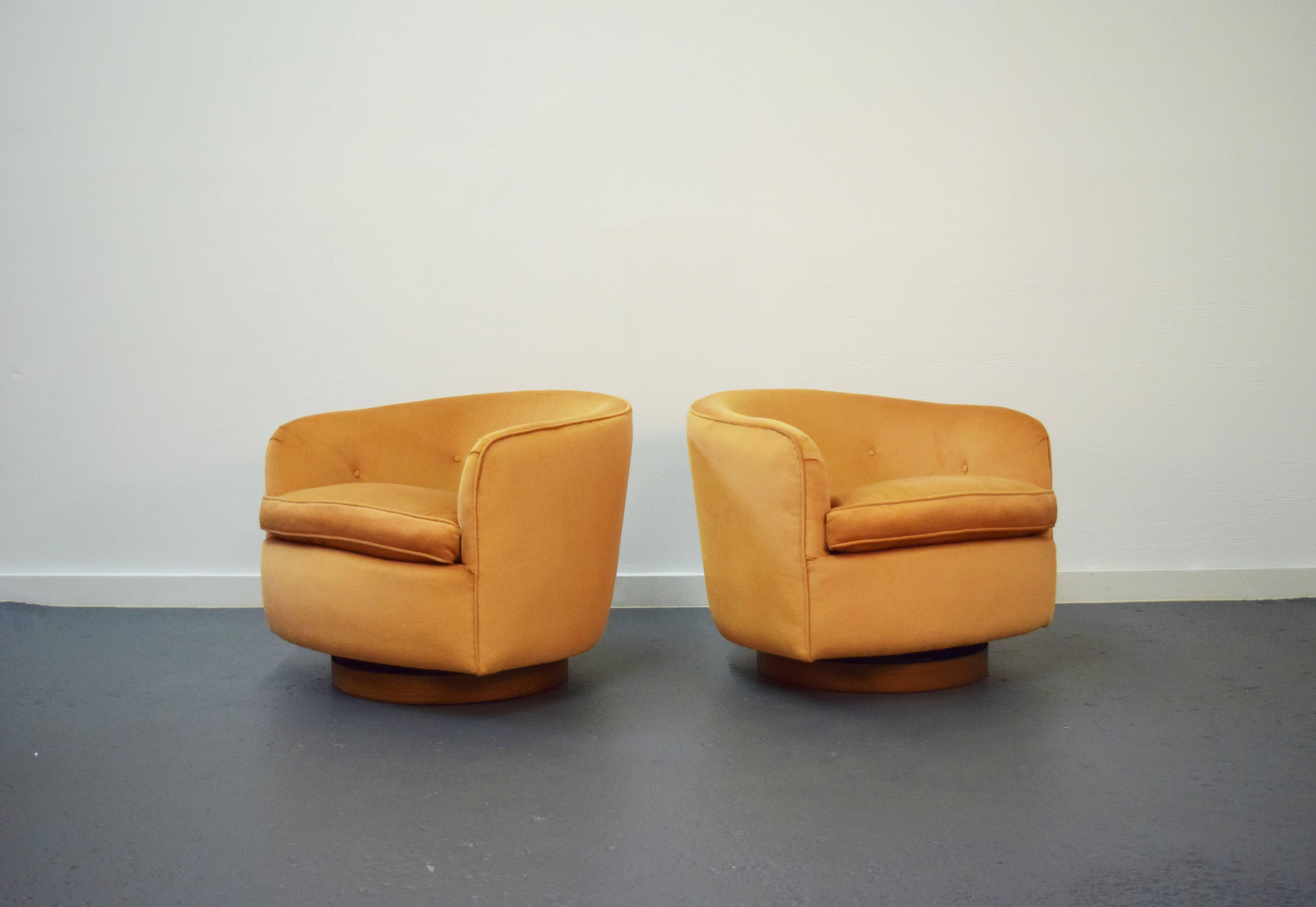 Pair of Milo Baughman swivel lounge chairs. Chairs sit on walnut bases, swivel, and tilt.