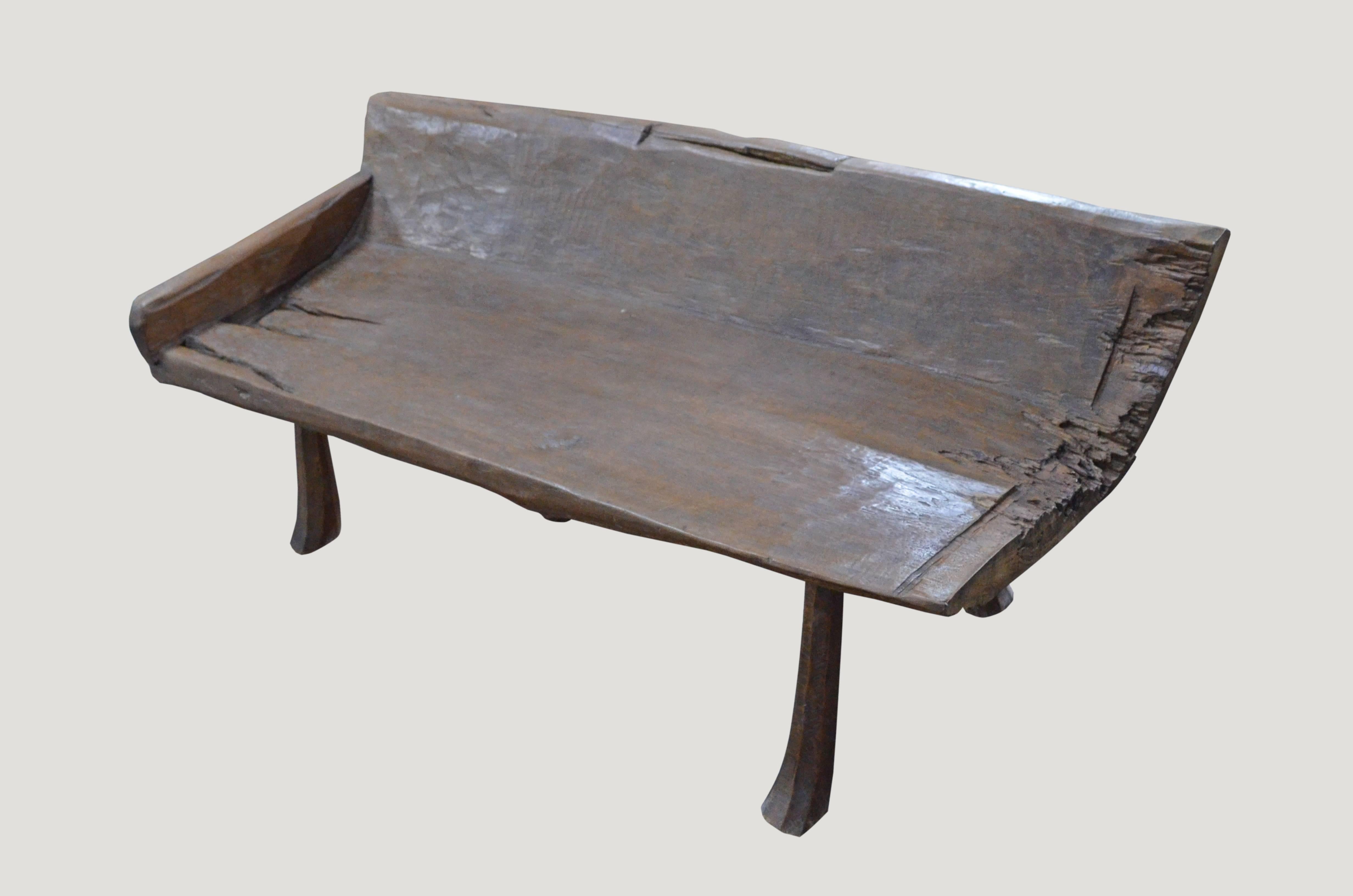 Stunning antique Primitive bench with beautiful patina made of teak wood. The seat section and back rest are carved from a single solid slab of aged teak wood. For the Primitive collector.

This bench was sourced in the spirit of wabi-sabi, a