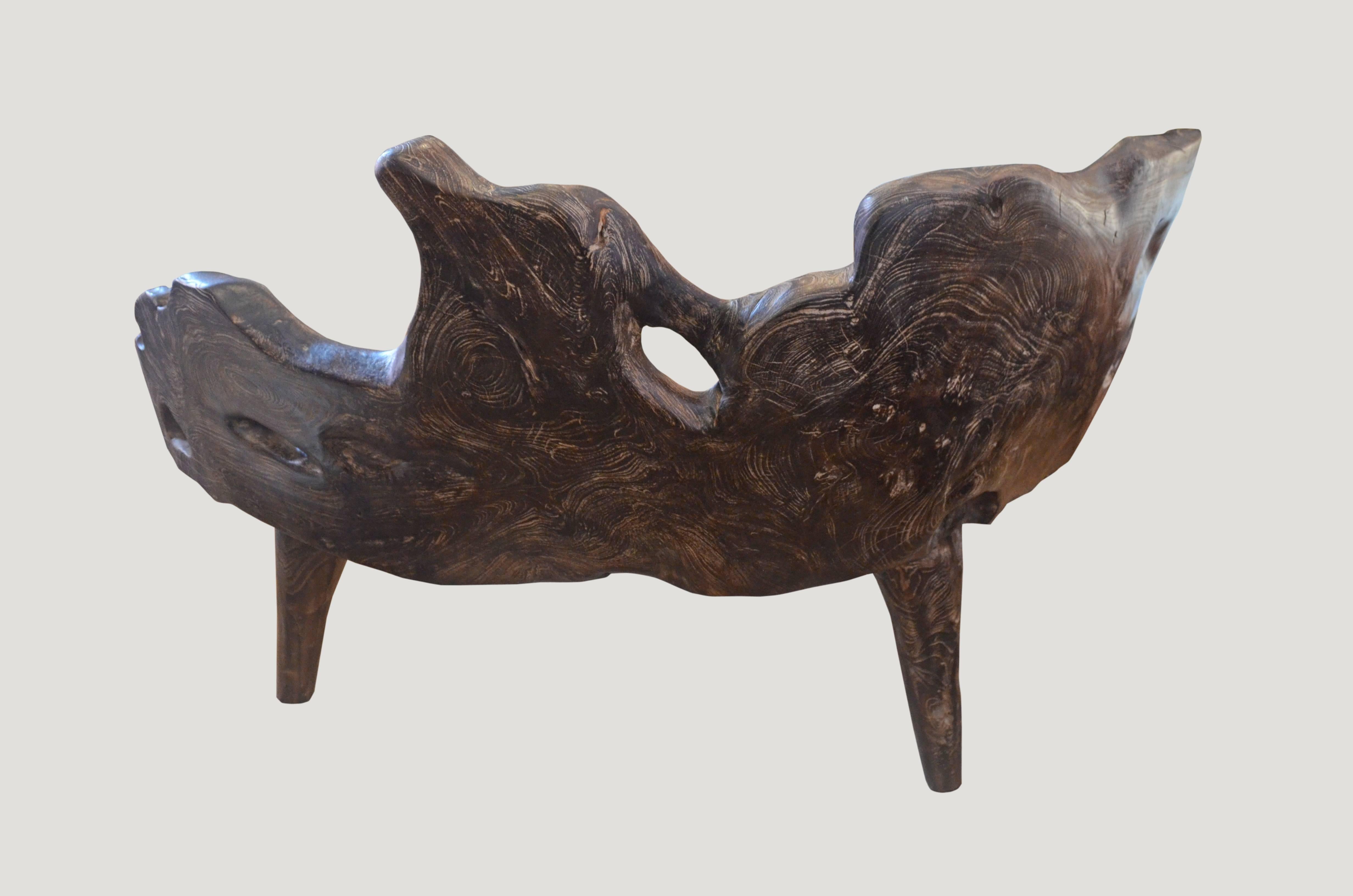 Organic shaped reclaimed teak bench carved from a single root found in the jungle in Sumatra. We added the legs, burnt it one time and finally added a cerused finish. The inside seat section is left natural teak and polished in contrast to the
