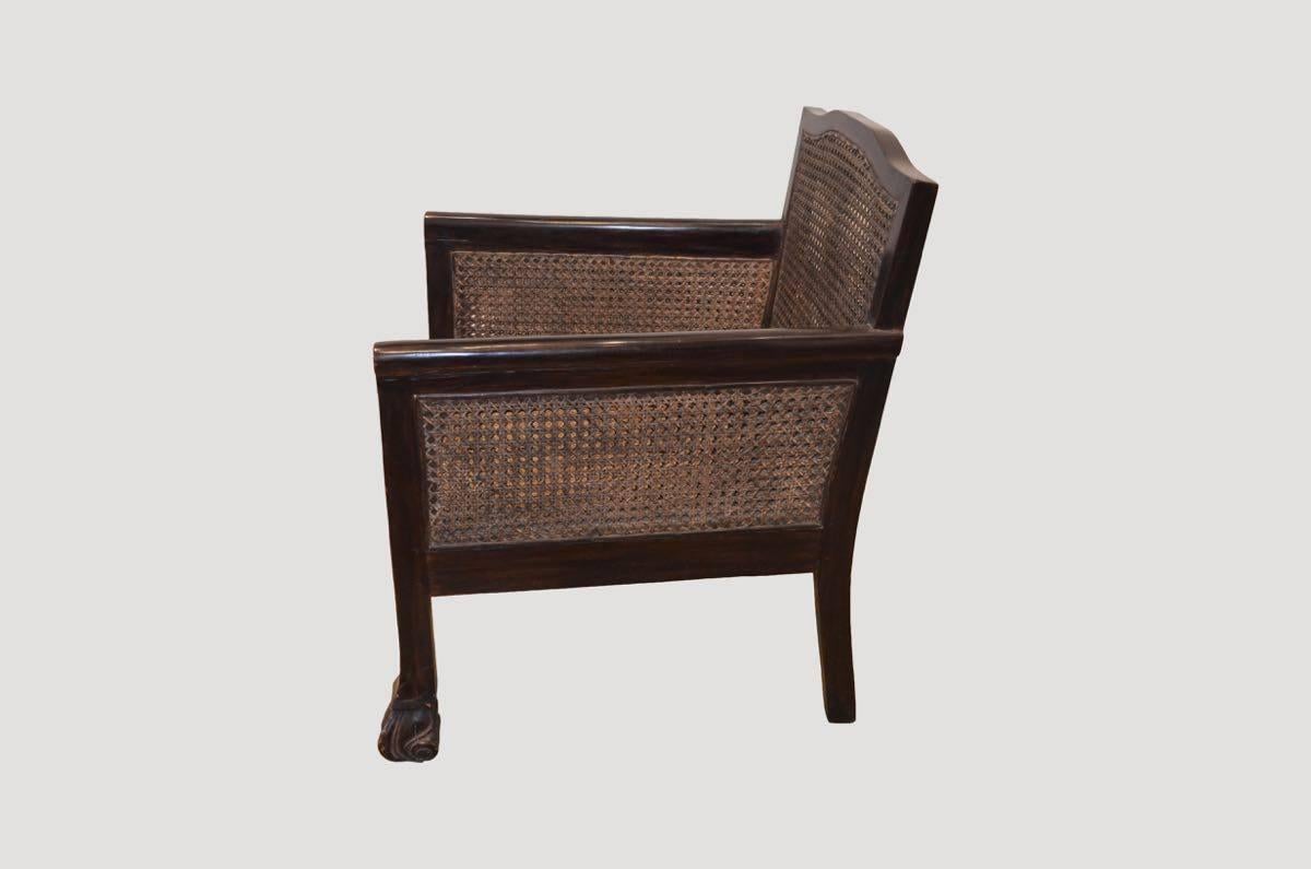 Beautiful reproduced Colonial chair. Hand-carved feet and double-backed handwoven rattan, makes this piece a Classic for any space. Includes linen pillow. Pair currently available. The price reflects one.