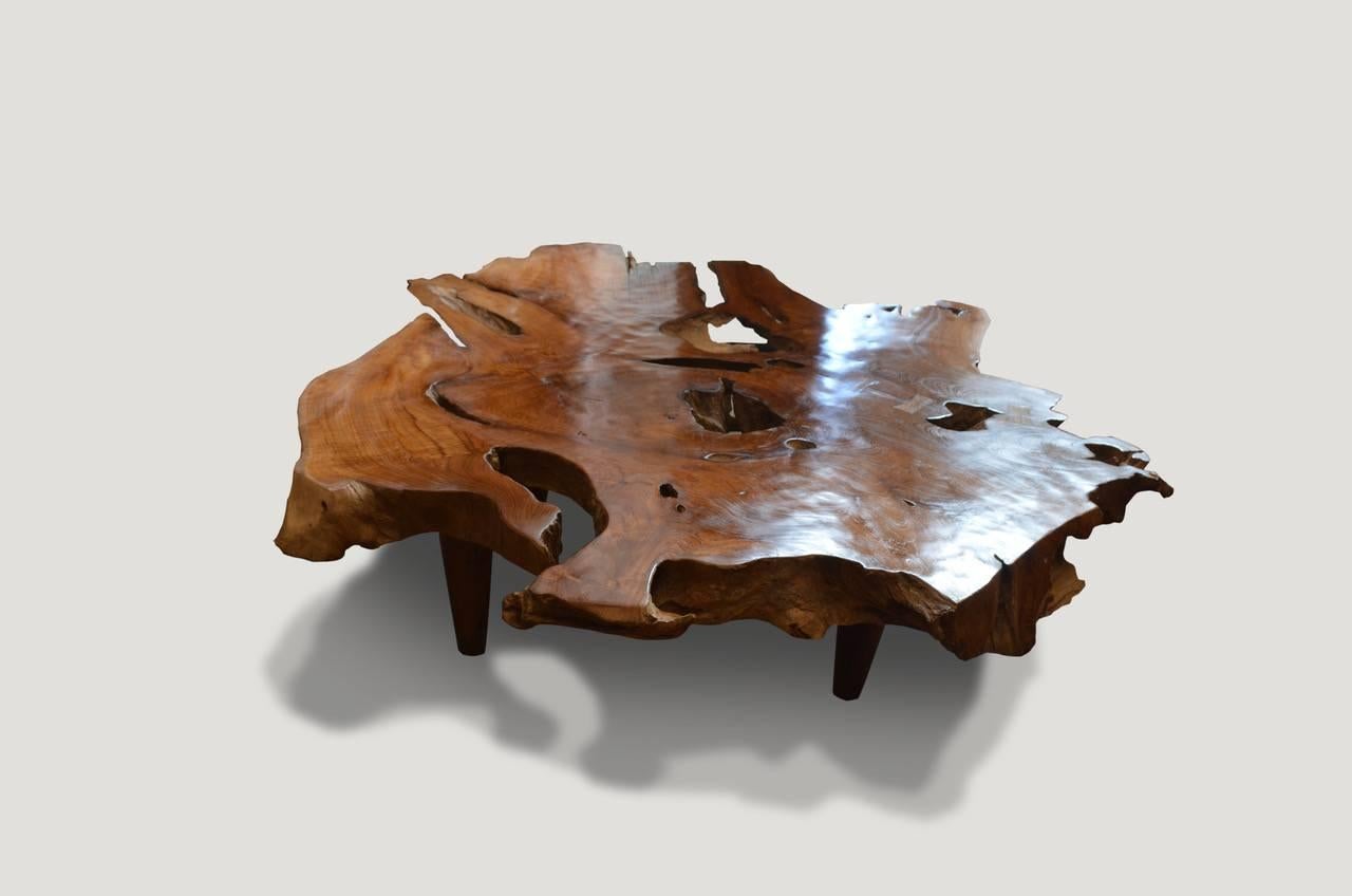 Impressive 4” single teak wood slab top coffee table. We have added butterfly details and midcentury style legs to this stunning organic shape and polished the top to enhance the grain in the reclaimed teak wood, whilst leaving sections of the sides