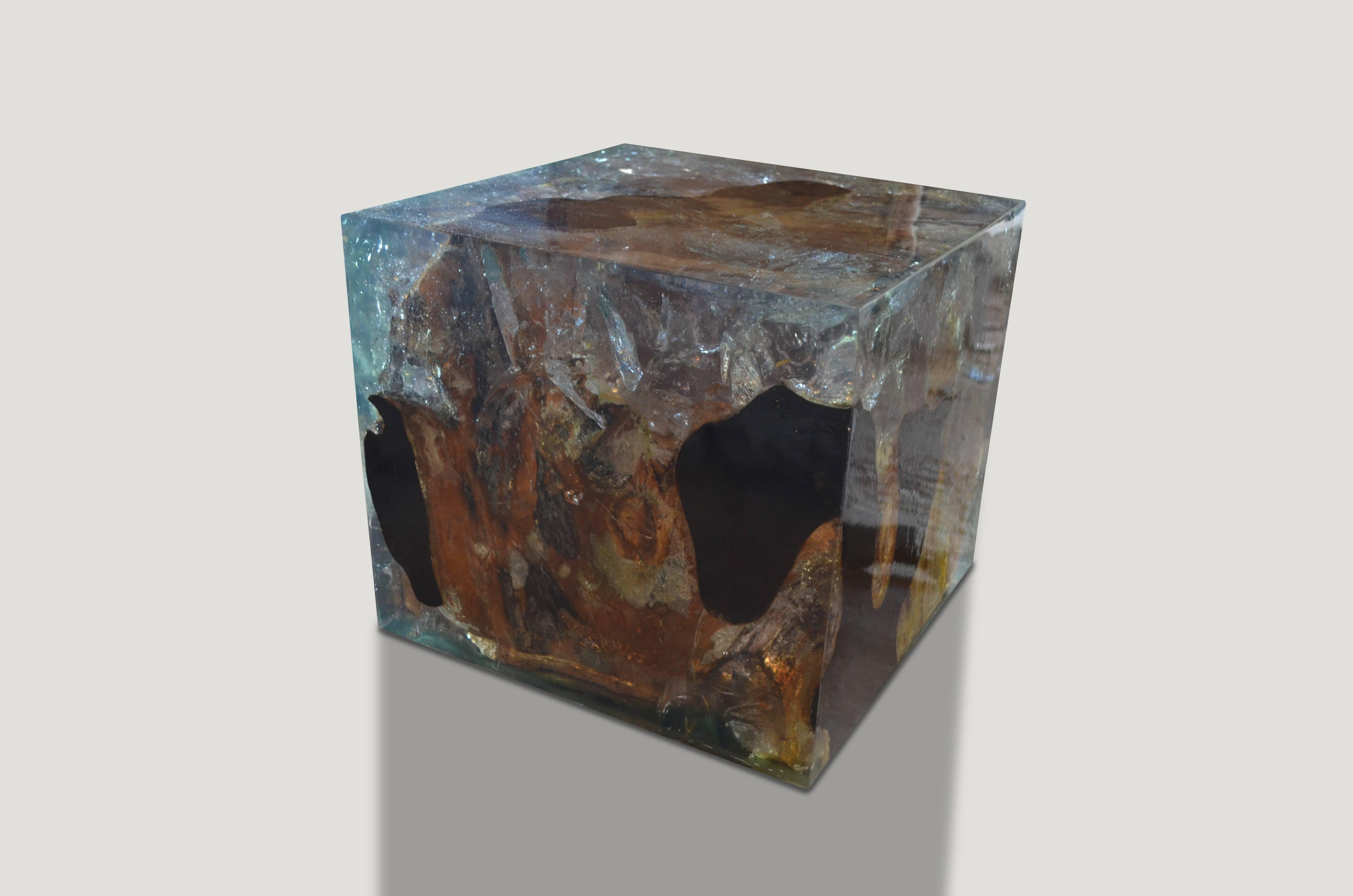 This cracked resin side table or cocktail table is made from reclaimed teak infused with aqua resin. A dramatic piece due to the depth of the resin, which resembles a unique quartz crystal with many different facets as shown here with gold, warm