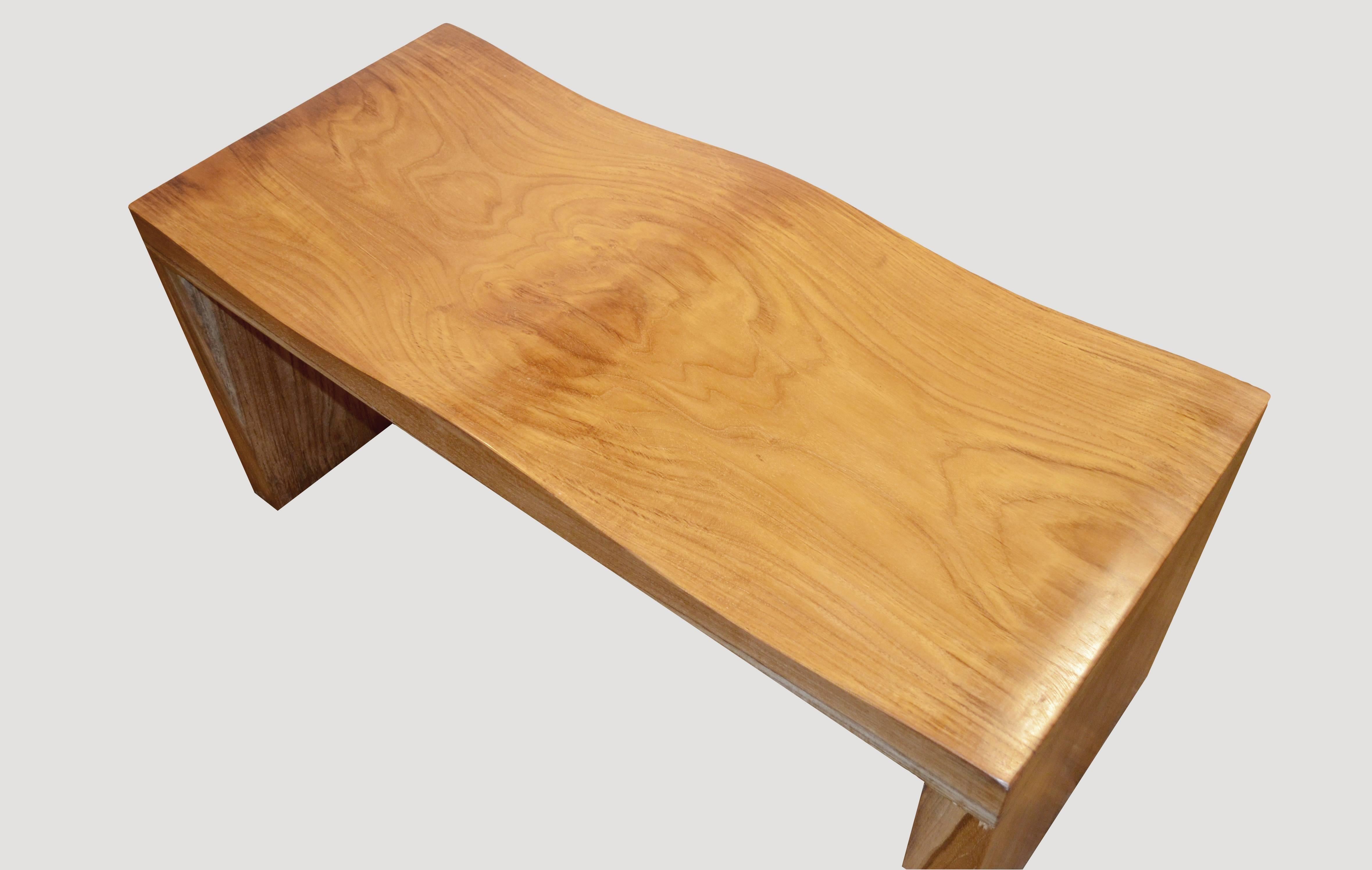 The top and legs of this particular wave bench is made from an impressive single 18″ wide x 2.5″ thick teak wood slab. Also available 12″ wide.

The teak wave bench represents a sleek, modern aesthetic, designed to provide comfort and durability.