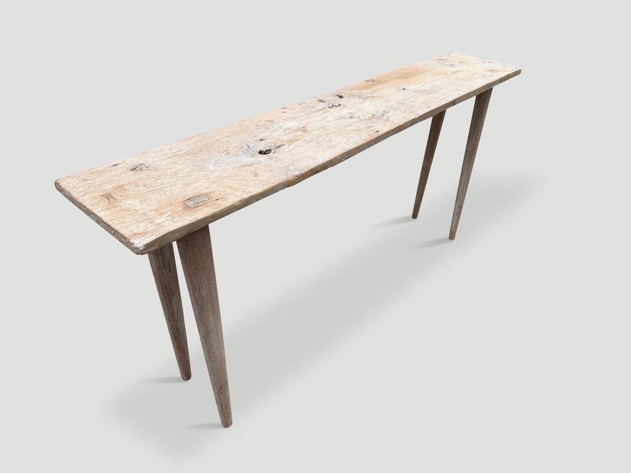 A single antique wood panel with lovely character. We added smooth teak minimalist legs and a butterfly inlaid into the top to form this beautiful console. First bleached and finished with a secret ingredient revealing the stunning wood grain. It’s