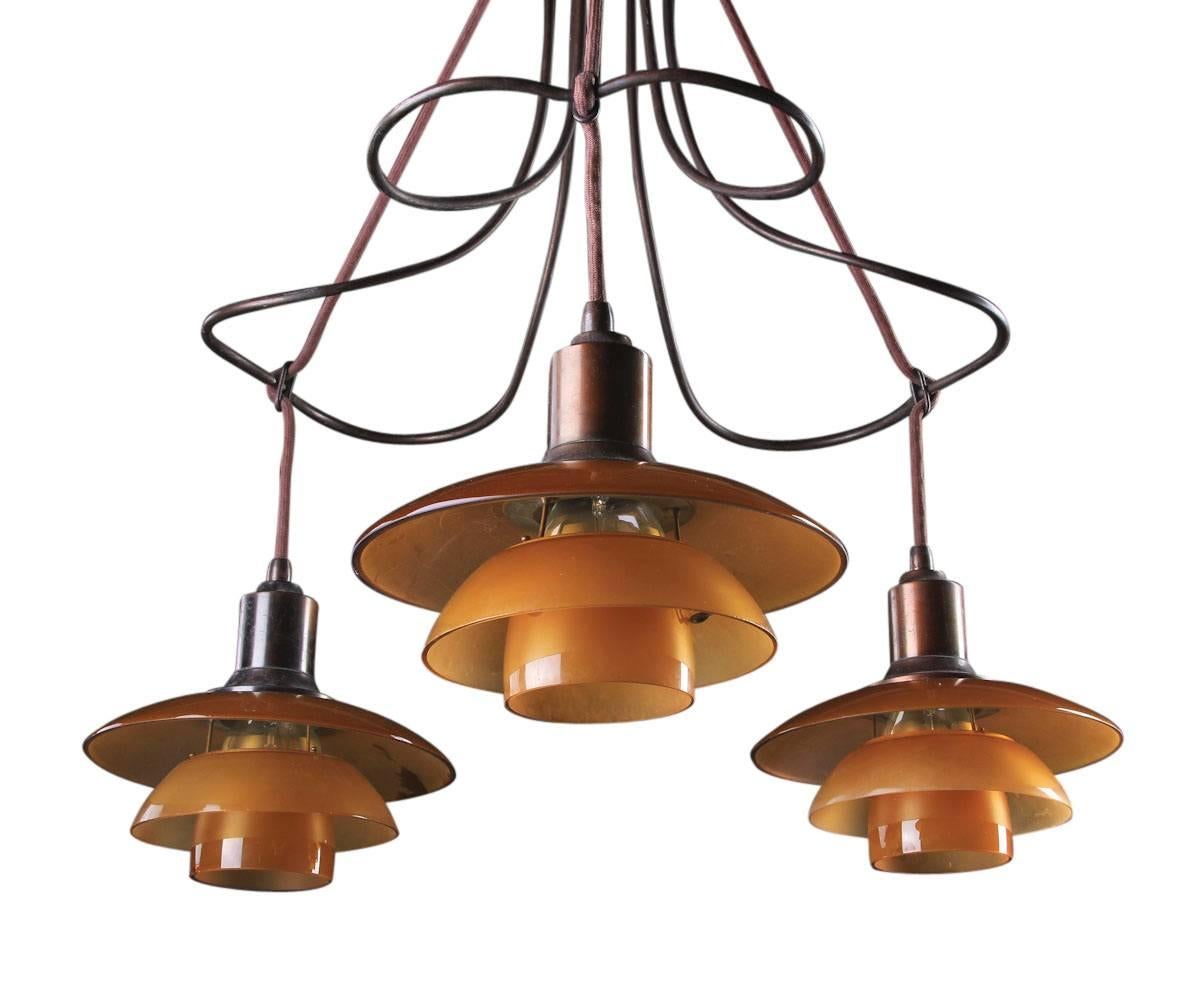 Poul Henningsen 2/2 'Butterfly' chandelier. Frame and socket holders of patinated brass, three lights with amber colored glass, bottom bowls of matte glass, shade holders stamped PH-2, patented.

This example manufactured 1931-1934 by Louis