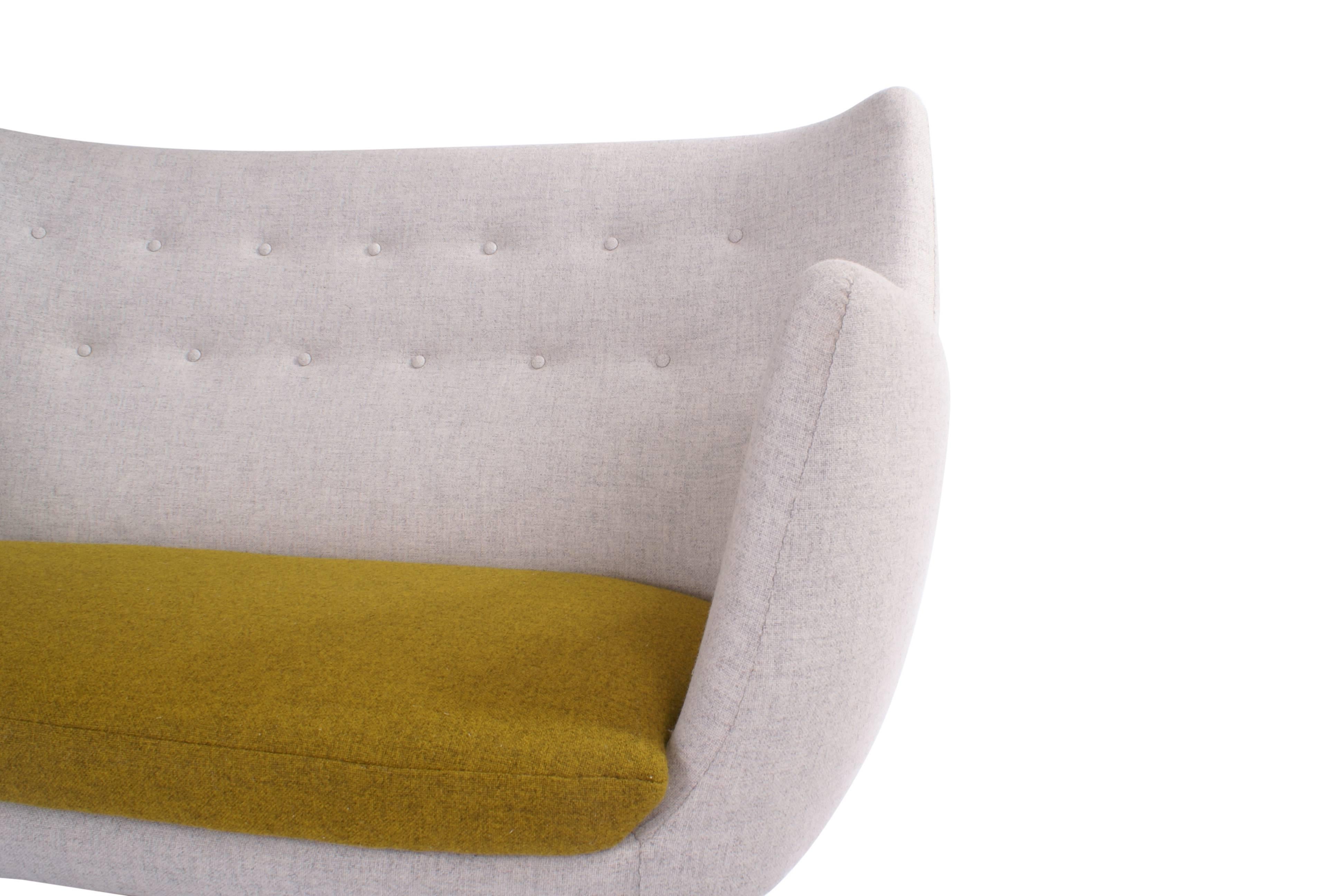 Finn Juhl 'Poet' settee for Niels Vodder.

Freestanding two-seat sofa with round, tapering legs. Sides and back upholstered with grey wool, loose seat cushion upholstered with dark yellow wool. Back fitted with buttons. Designed 1941.

For