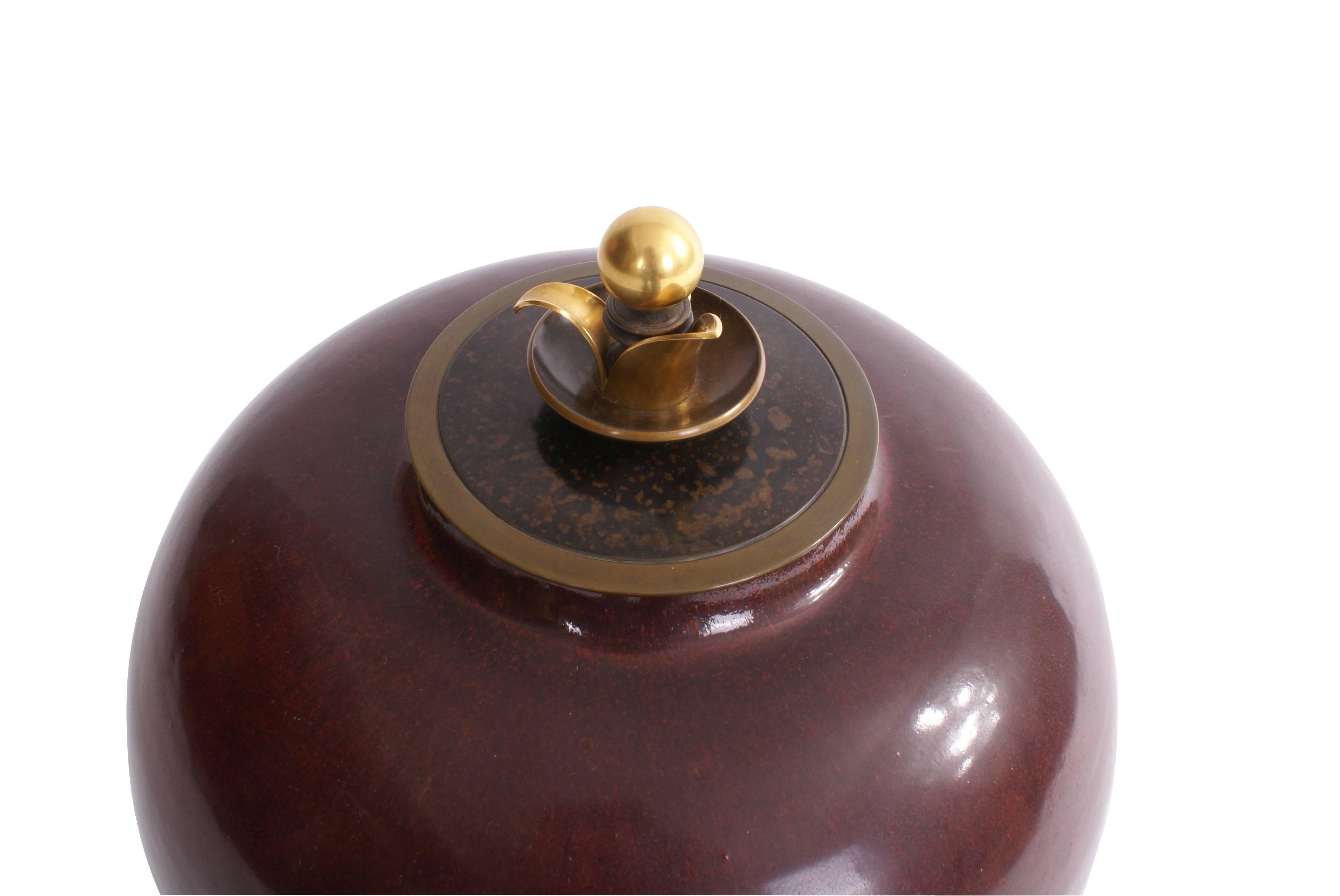 Large Kresten Bloch stoneware jar decorated with oxblood glaze with lid and Stand. Lid and Stand of patinated and partly gilded bronze. Stamped monogram KA for Knud Andersen. Royal Copenhagen. This piece is unique.

Signed monogram. 'Royal