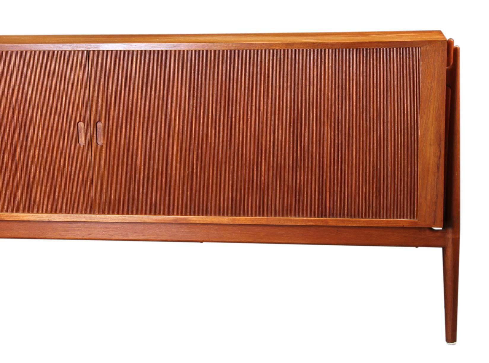 Niels Vodder large NV54 sideboard in teak with two tambour doors over eight pullout trays on left and one adjustable shelf on right. Designed, 1954. Made by master cabinetmaker Niels Vodder.

Literature: Danish Design Museum, no RP02547.