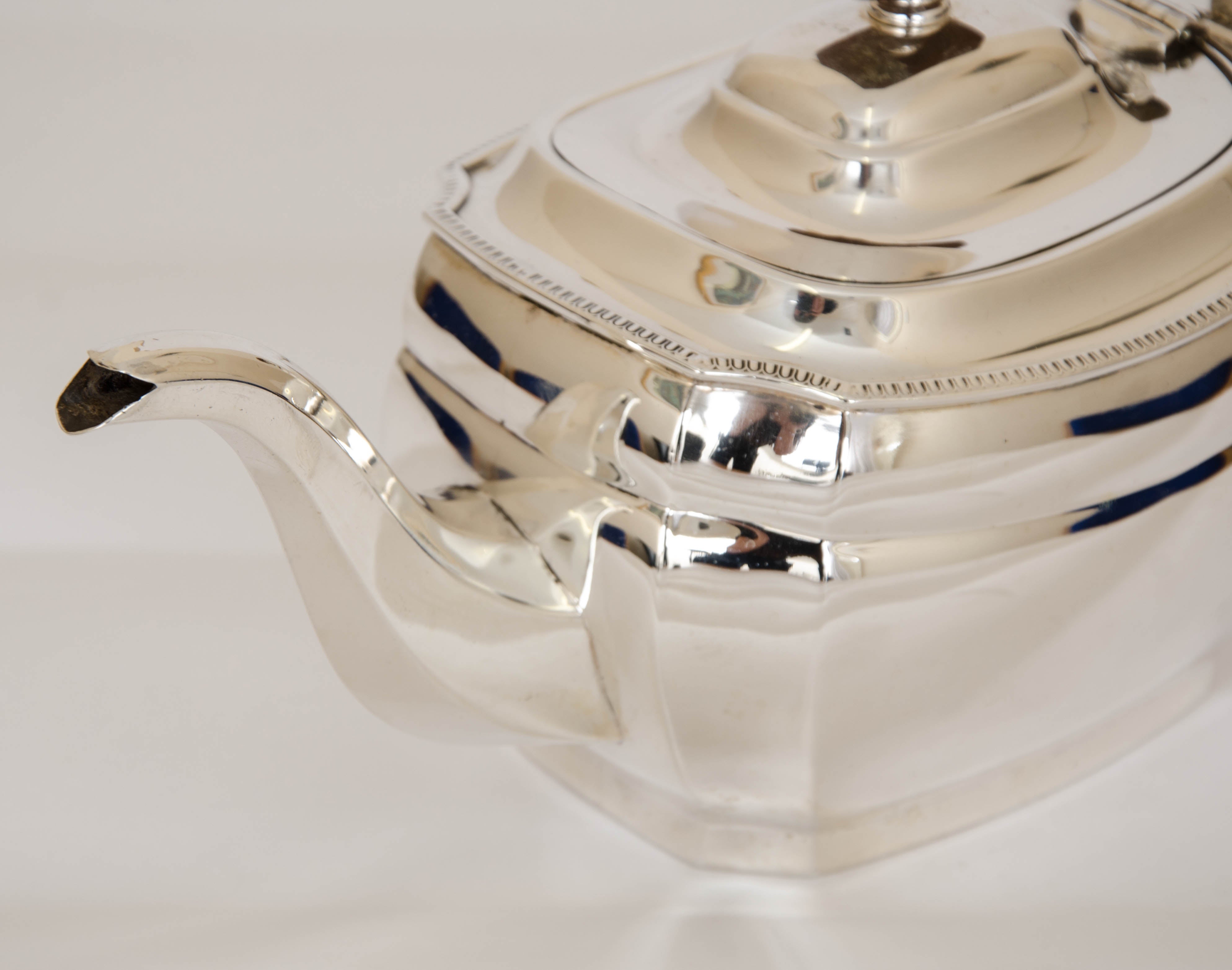 Sterling silver teapot made in the reign of George V. The pot is of faceted rectangular form, with fruitwood finial and handle and an egg and tongue border. Height 5.5 inches 14 cm Length 11.5 inches 29.3 cm Made by James William Benson.