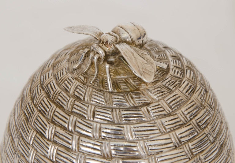 A magnificent Victorian Antique Silver Honey Pot, of traditional skep form (a beehive made of horizontal coils of straw). The pull off lid is capped with a realist model of a bee.  The interior of the base contains a glass dish for the honey. The