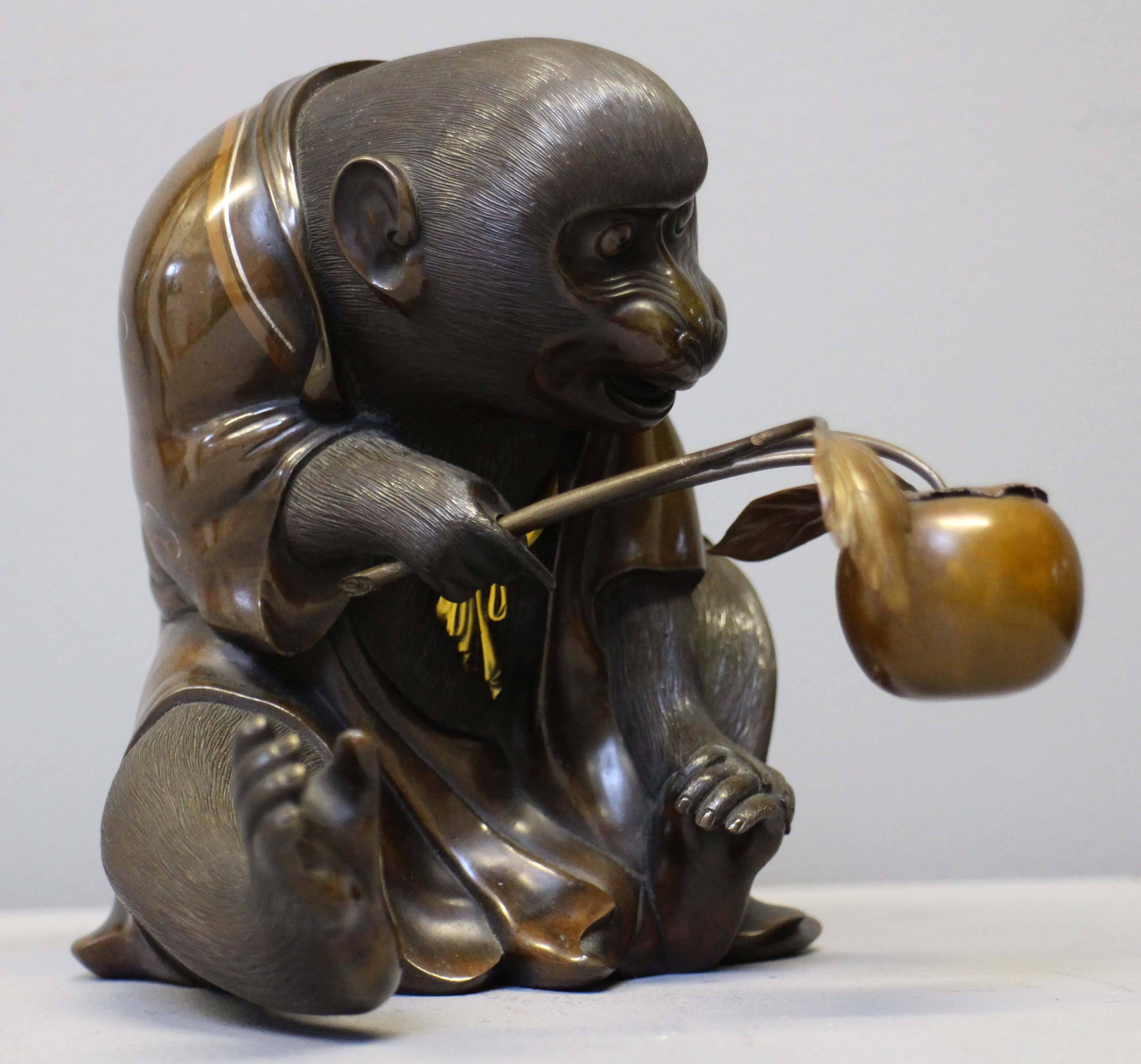 An unusual antique Japanese bronze monkey with multimetal inlaid decoration, wearing a copper coloured kimono, decorated with detailed silvered origami cranes, holding a large peach on a branch.

The multimetal inlay and natural antique patina of