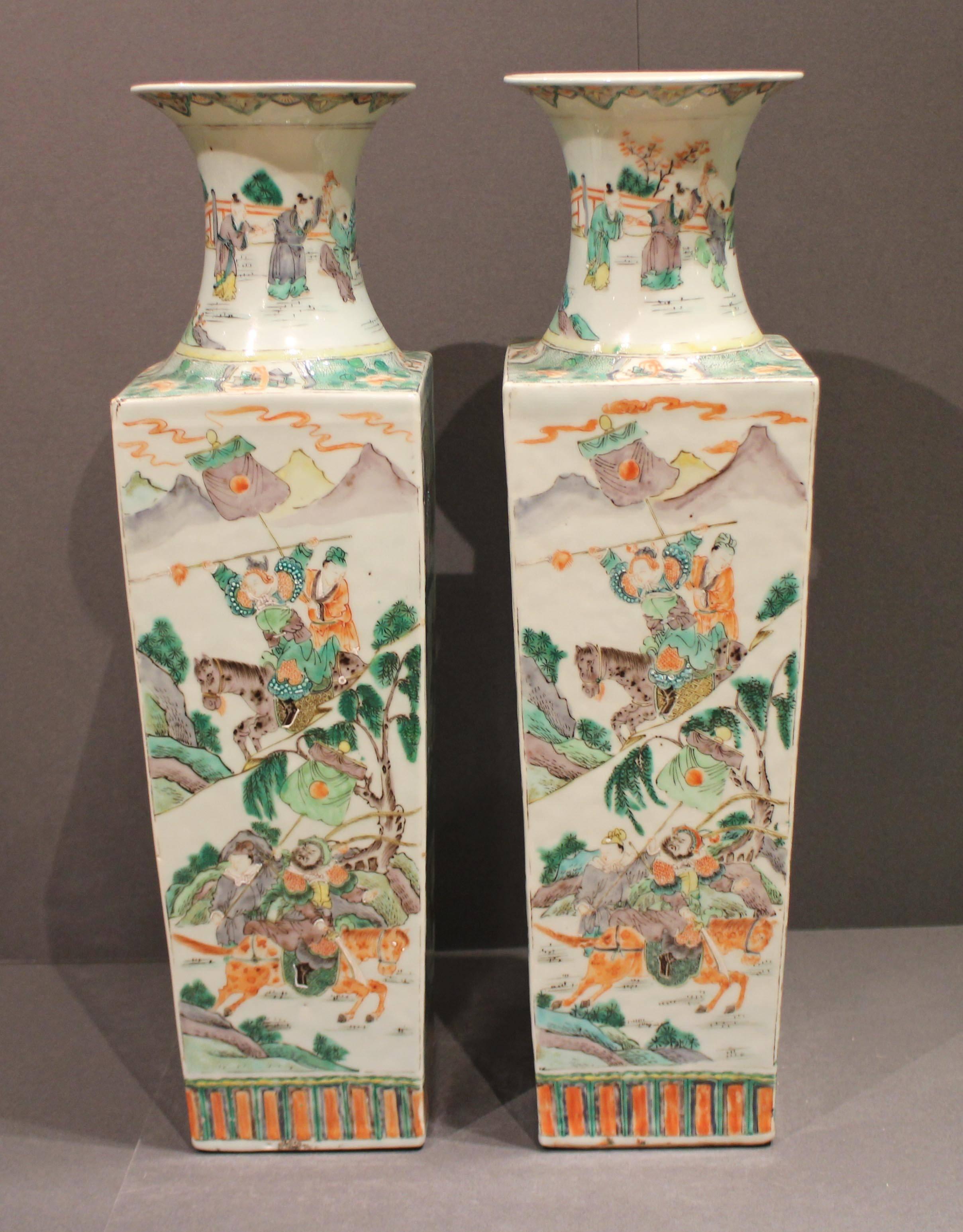 A pair of antique square shaped Chinese famille verte vases, decorated in delicate green, grey and orange with scenes including warriors fighting, a man training a dog and figures in interiors.