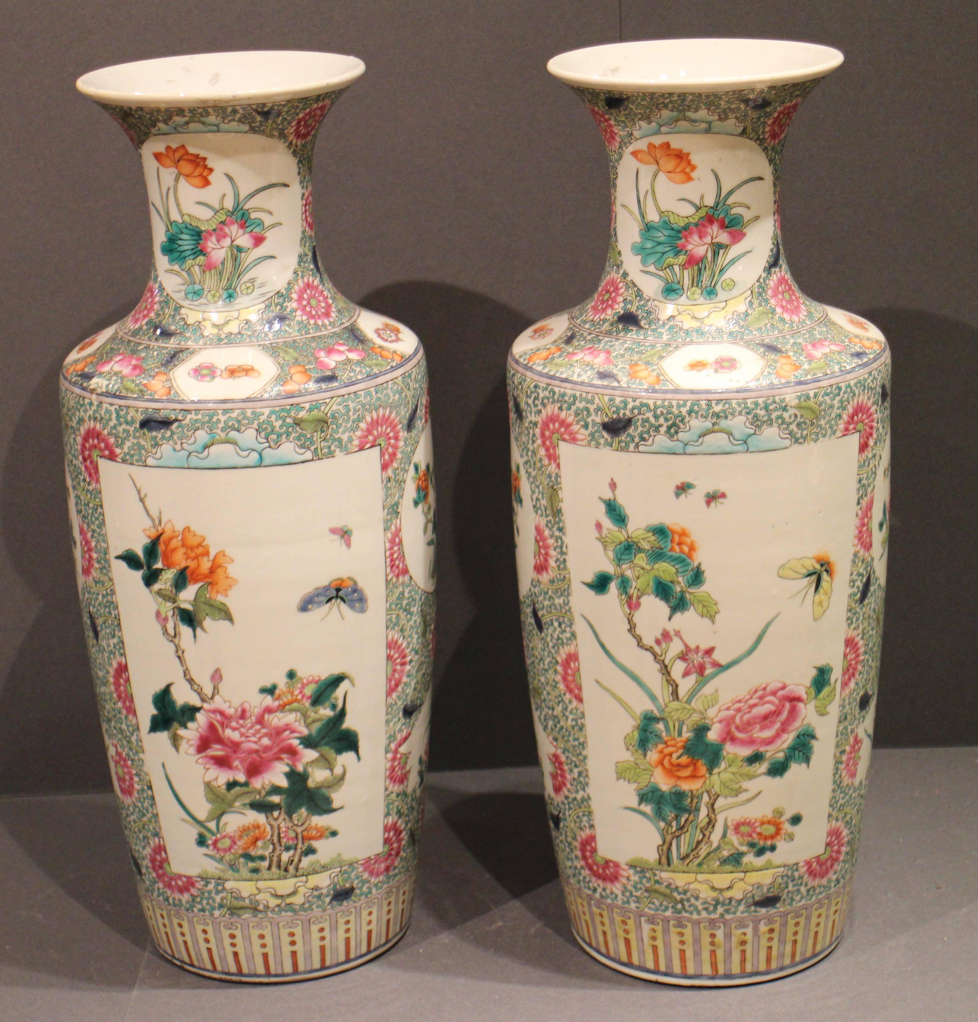 A fine pair of antique Chinese famille verte vases decorated with finely painted panels of butterflies and flowers on a green and pink floral ground.