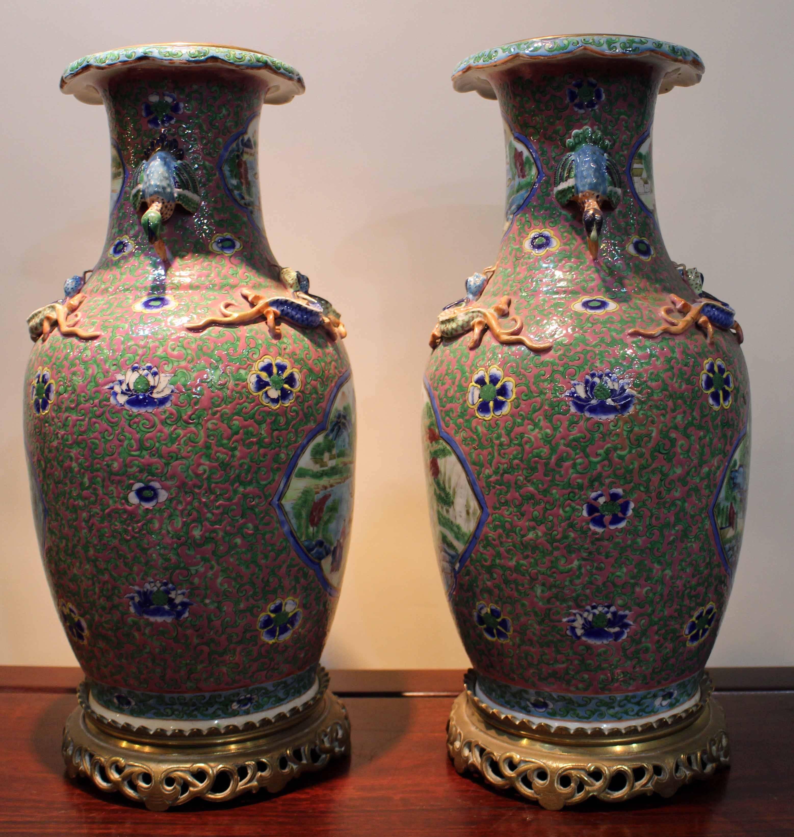 A pair of unusual antique Chinese vases with famile verte panels on ormolu bases, decorated with  panels of figures in landscapes on a green and pink pattern ground.

