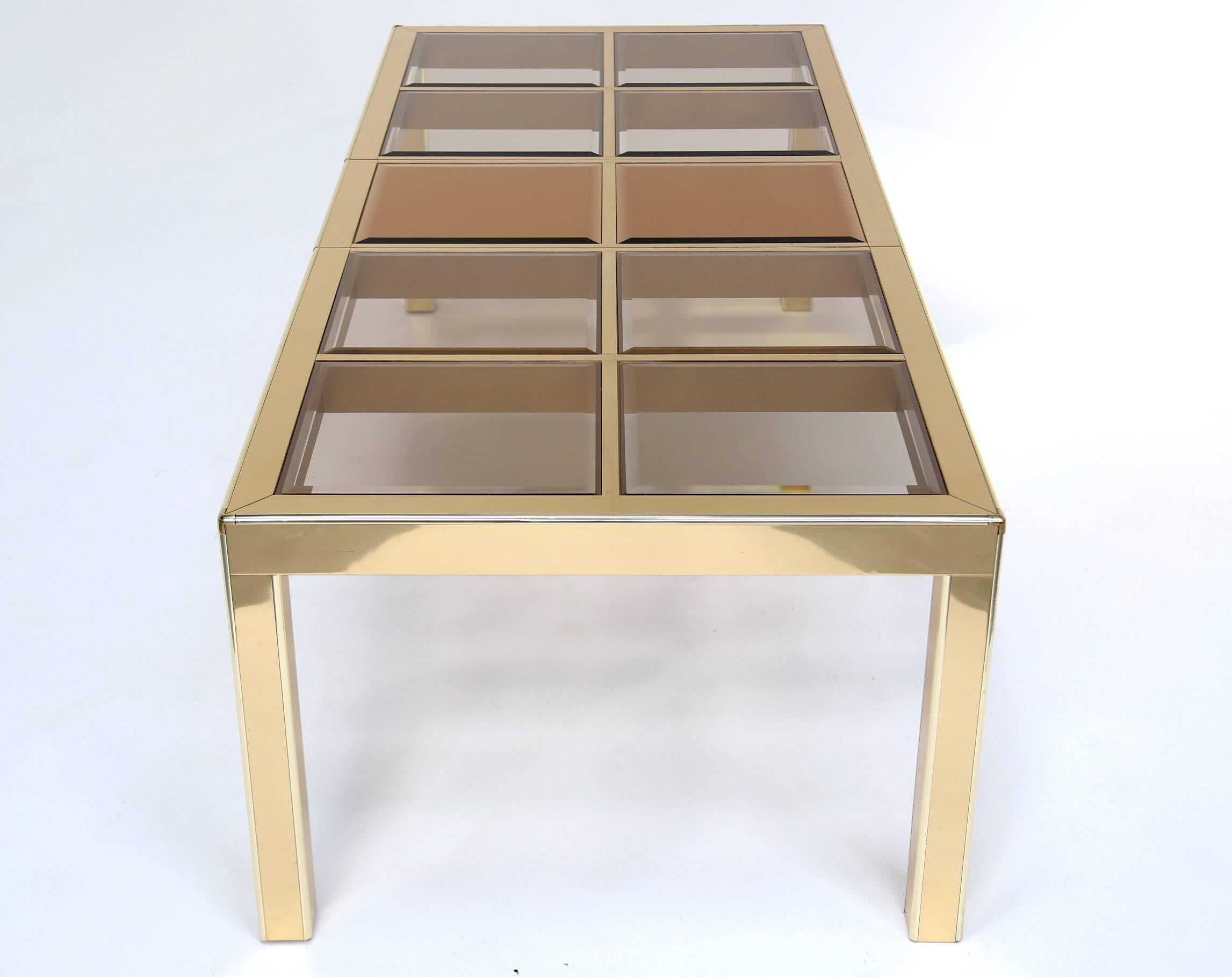 A superb quality brass extending dining table by Mastercraft, made in the 1970s using a plated brass table with a mix of smoked and mirrored glass panels. Its a very solid table and a generous size, perfect for entertaining large groups. Looks great