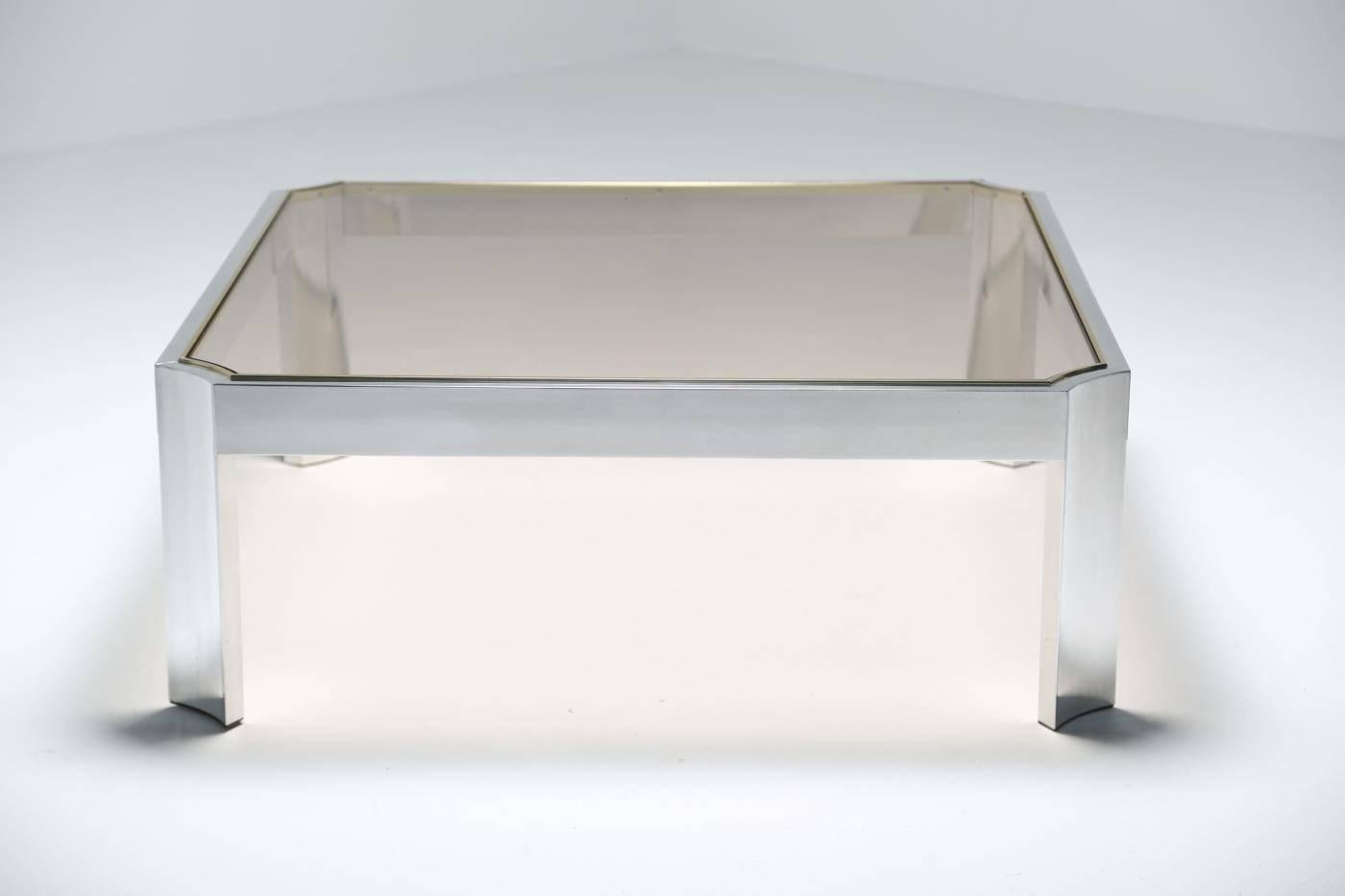 An aluminum and glass coffee table with brass trim surrounding the glass, in the style of Ron Seff. A good looking coffee table and a generous sized one too, see dimensions. Easily shipped anywhere in the world.