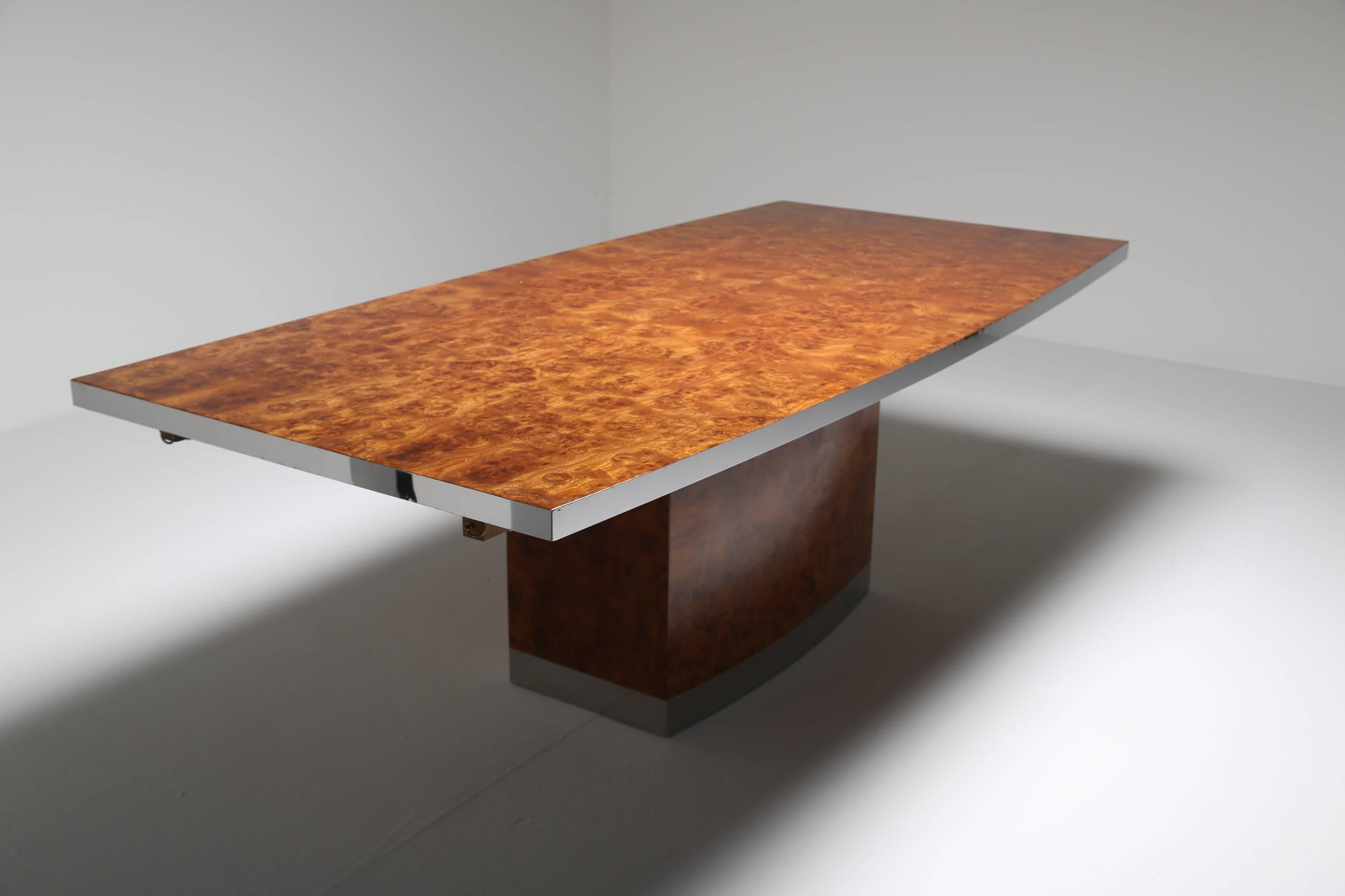 A Jean Claude Mahey maple burl dining table with chrome trim. The maple dining table top sits on a pedestal base. The bottom chrome trim on the base is feigntly signed JC Mahey. This table has been refinished on the top and is in immaculate