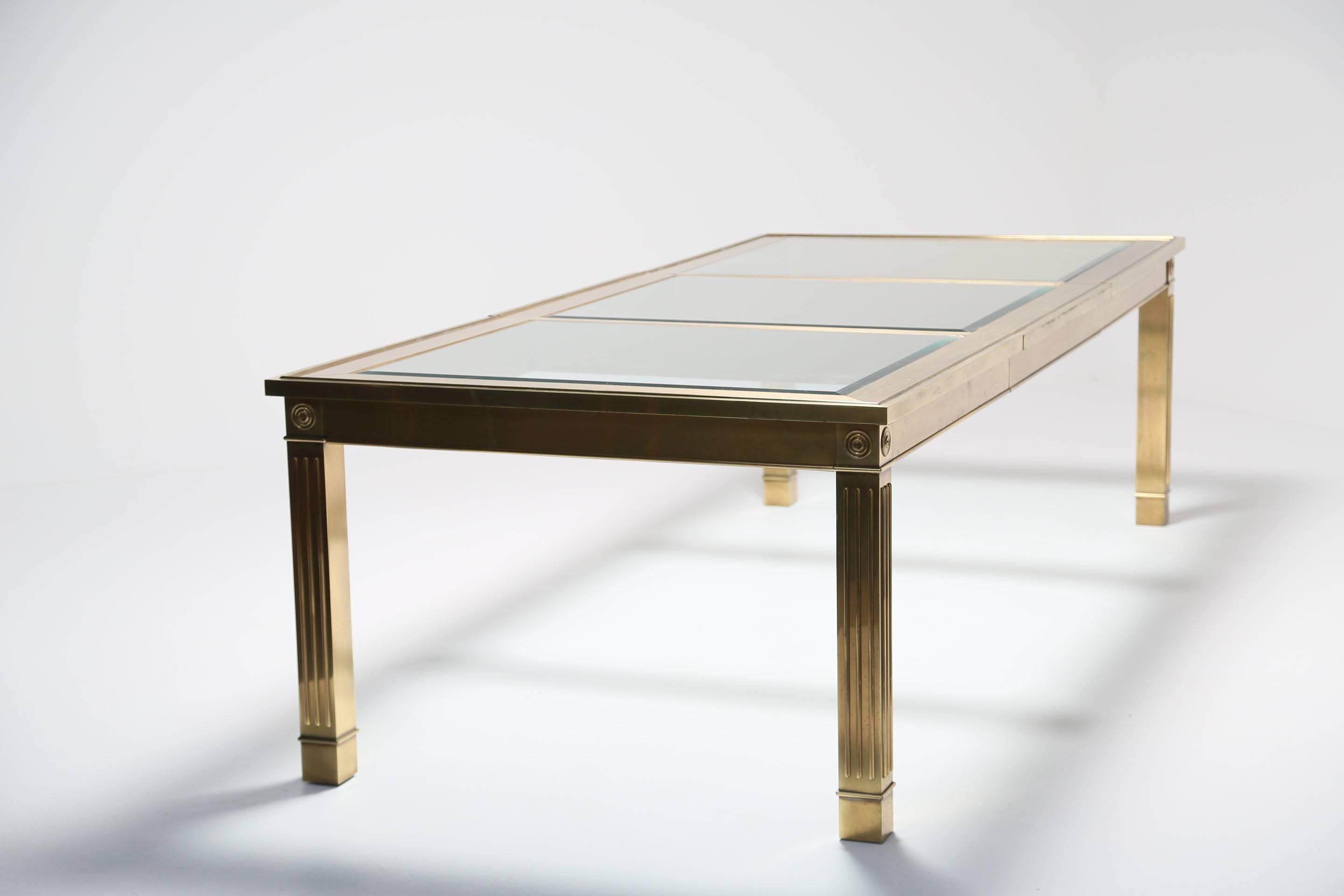 An extending brass and glass dining table by Mastercraft with one large spare leaf. A really beautiful and large dining table with beveled glass top. The table is plated brass and there are a few areas where the brass has been rubbed. Chairs