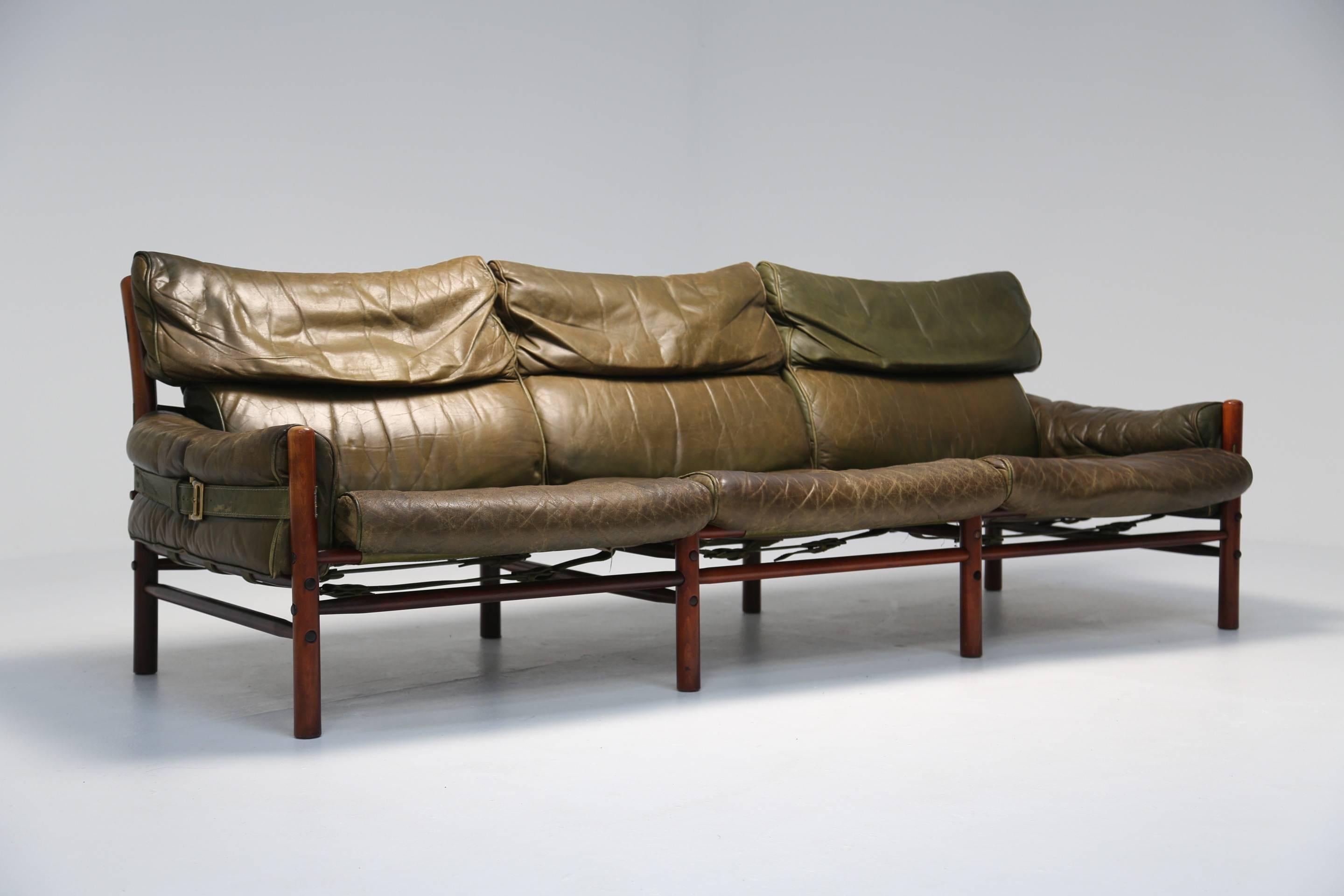 A handsome example of the Classic 'Kontiki' sofa designed by Arne Norell. Produced by Mobel AB Arne Norell, Sweden, circa 1970 this three-seat sofa has a richly colored wooden frame and uses beautifully worn green leather.