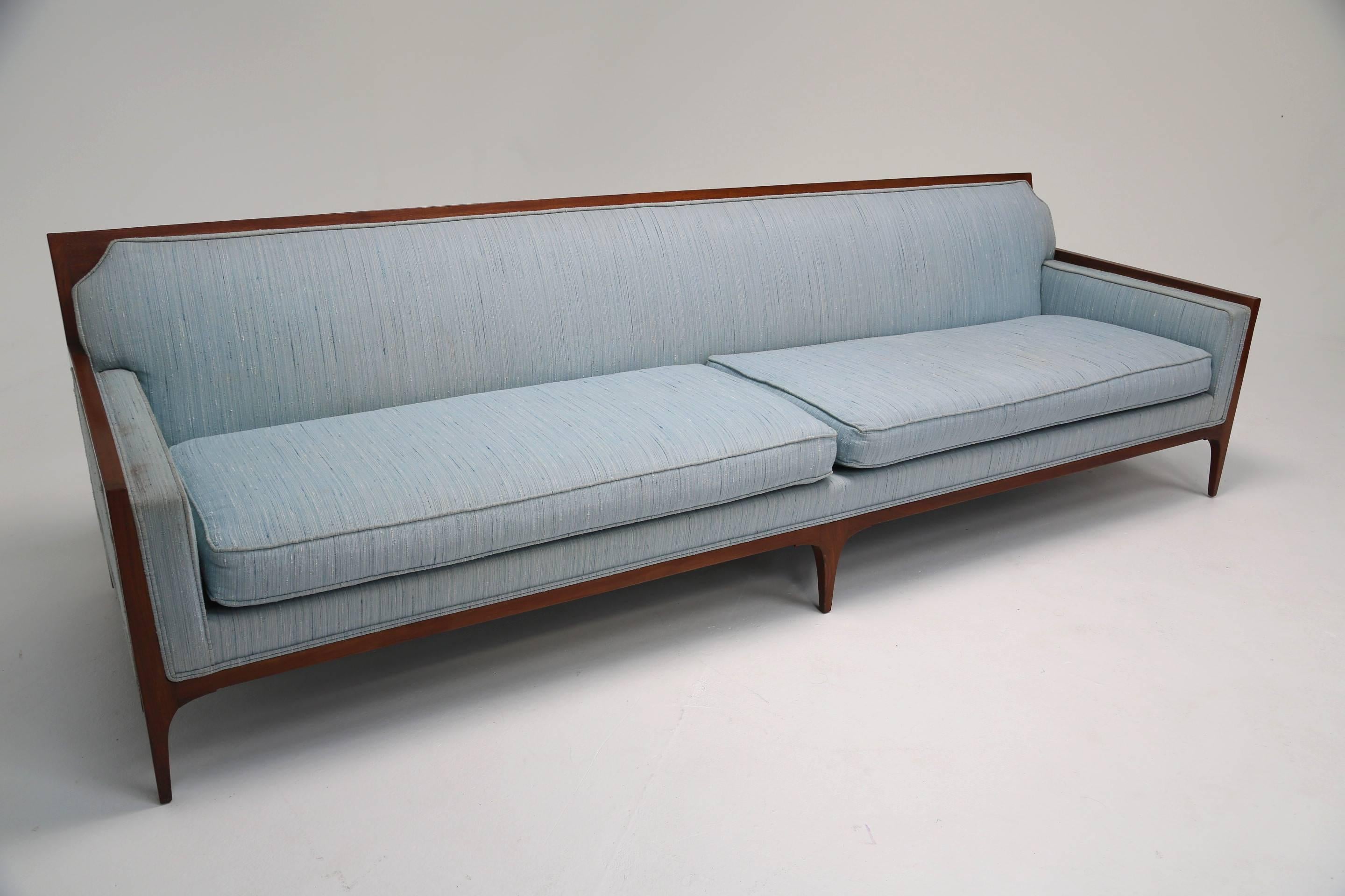 This elegant 1950s four-seat sofa in the style of Paul McCobb, is upholstered in a pale blue fabric with a walnut frame. Beautiful lines have been employed in it's design to offer the piece a Classic quality whilst the sturdy walnut frame offers an