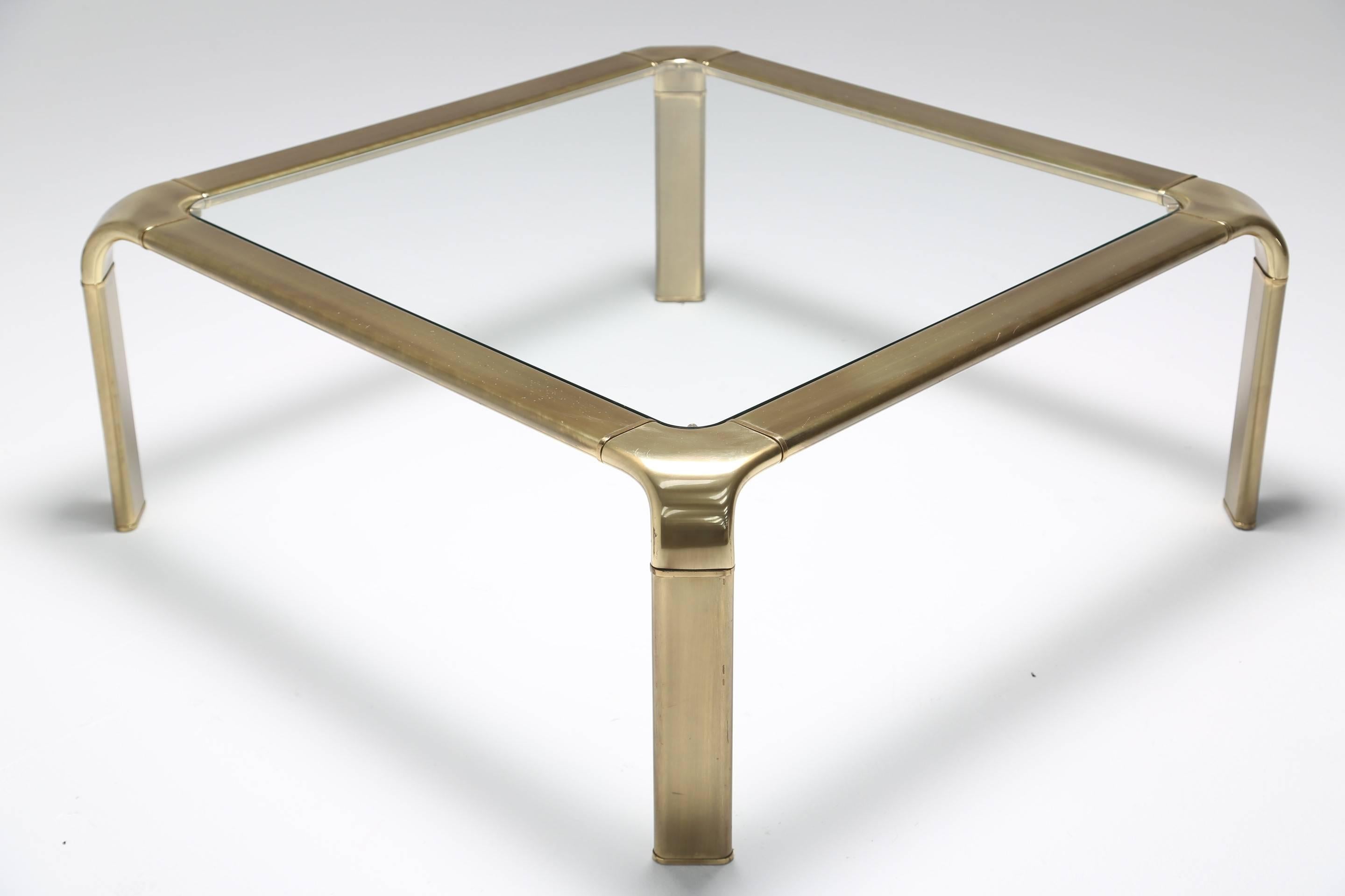 A beautiful 1970s waterfall coffee or cocktail table in patinated brass with fitted glass top. A very generous sized and solid coffee table, made in the USA by American furniture company Widdicomb. Very easily shipped worldwide.