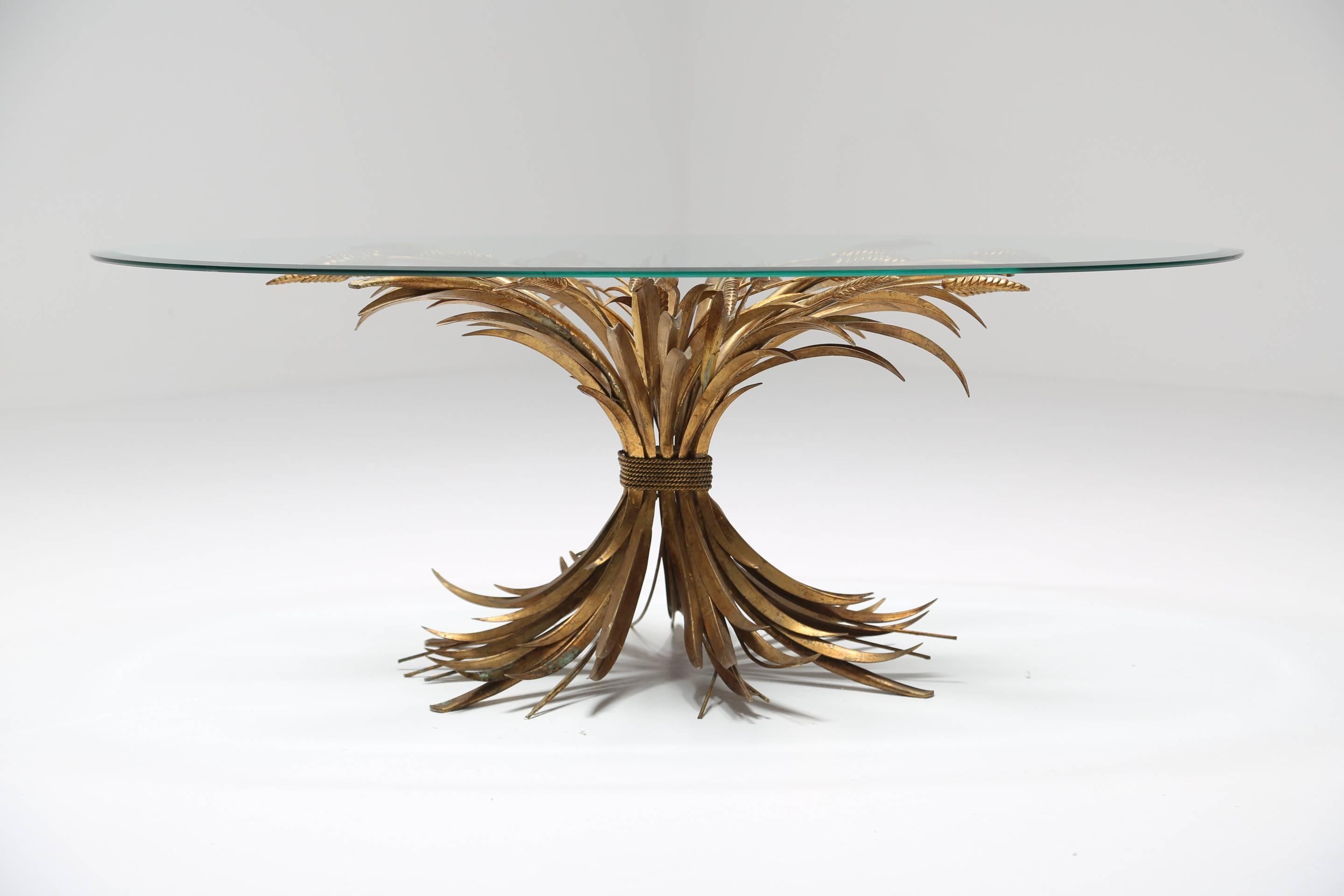 An oval glass coffee or cocktail table with a beautiful gilt iron sheaf of wheat base. This elegant Italian table designed by S. Salvadori is an iconic Mid-Century piece and unusually was designed to have an oval glass top rather than the more