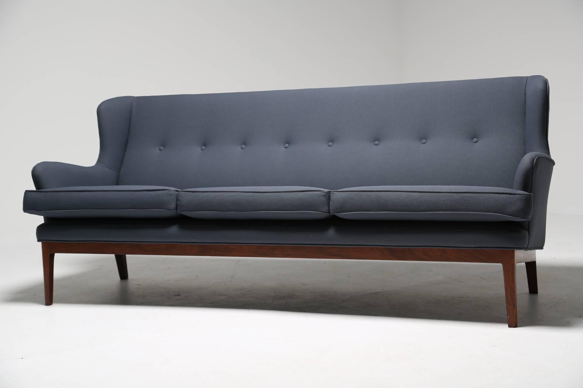 A Mid-Century Scandinavian modern winged sofa with tropical hardwood frame by Arne Norell. The sofa has been recovered in an original Danish fabric that would have been found on sofas of this period. A very comfortable sofa. We have a similar winged