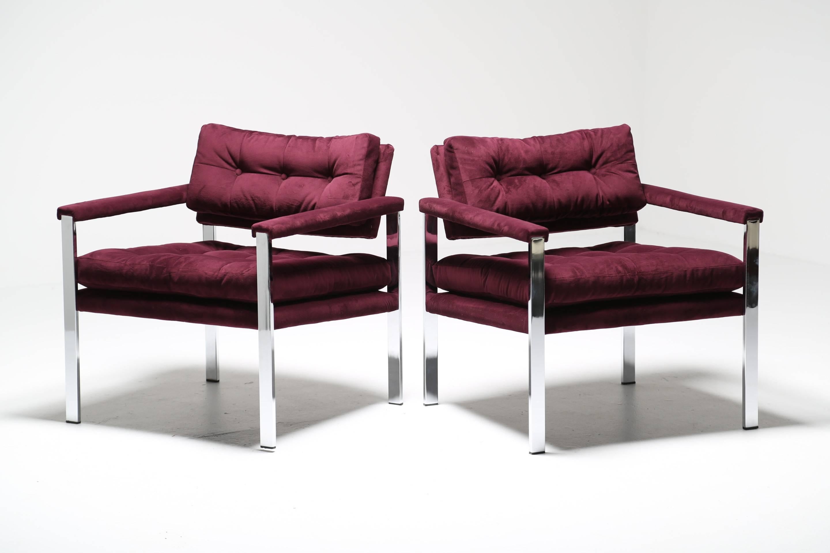 A pair of chrome frame lounge chairs recovered in a purple velvet, manufactured by Selig. A nice soft cushioned seat that makes for a very comfortable chair to sit in. The seat cushions are attached to the frame. The chairs have original paper