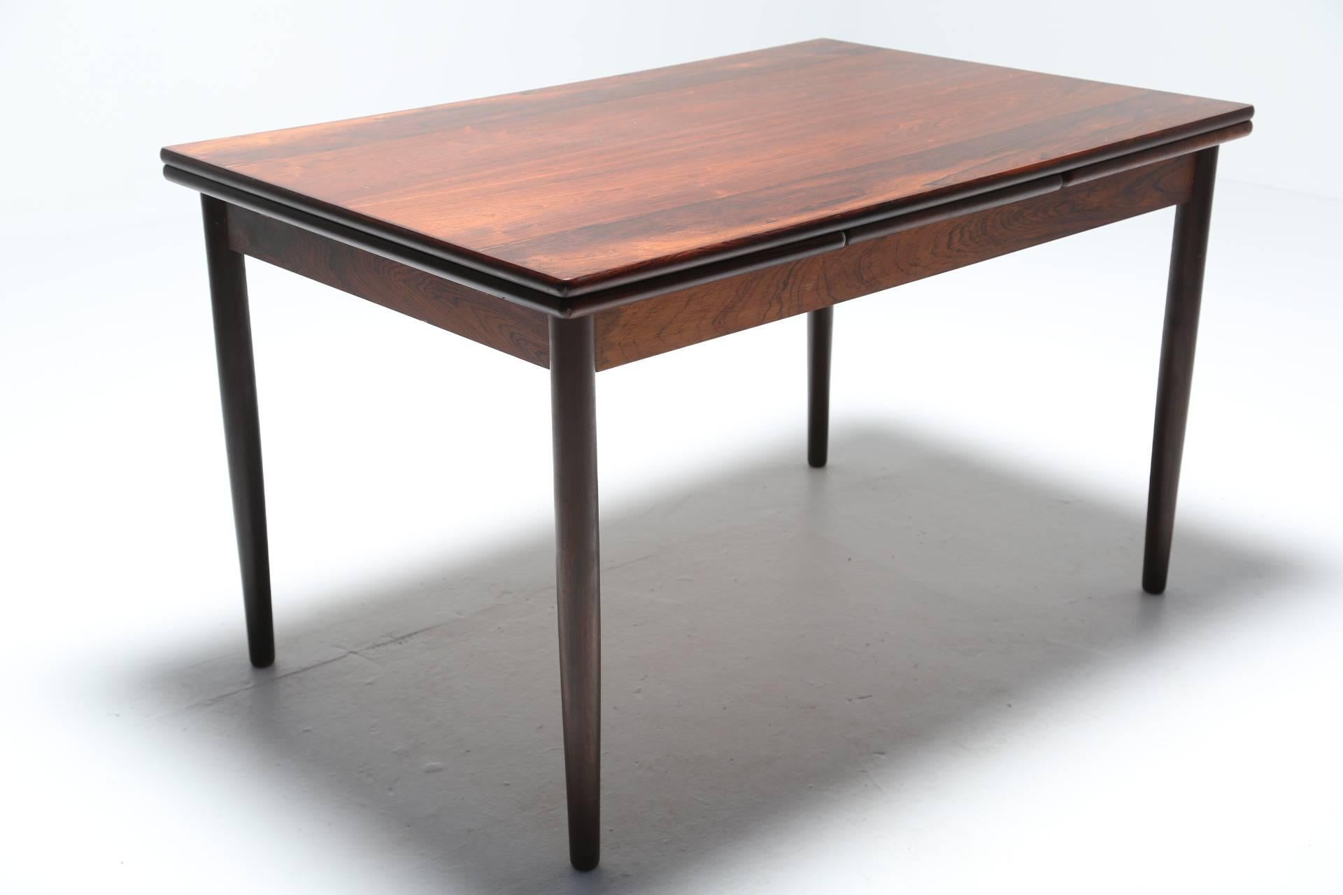 A beautiful Mid-Century Danish rosewood extendable table was that is very much in the style of Niels O. Moller. The wood is absolutely stunning and has a continuous grain and deep rich tones of fiery red and black. With two leaves for extending the