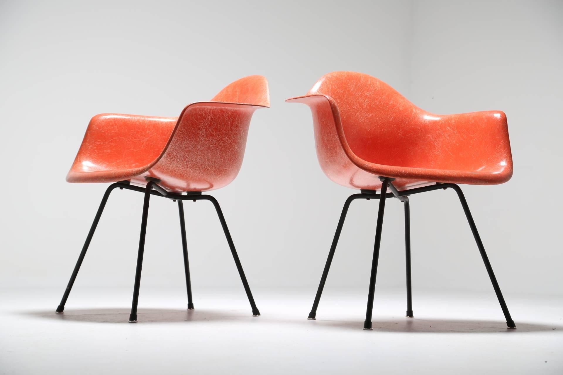 This is a fabulous set of second generation Zenith fiberglass Dax chairs in a vibrant orange on black steel X-base that have become an iconic staple of Mid-Century design. Designed by Charles & Ray Eames for Herman Miller, these chairs are