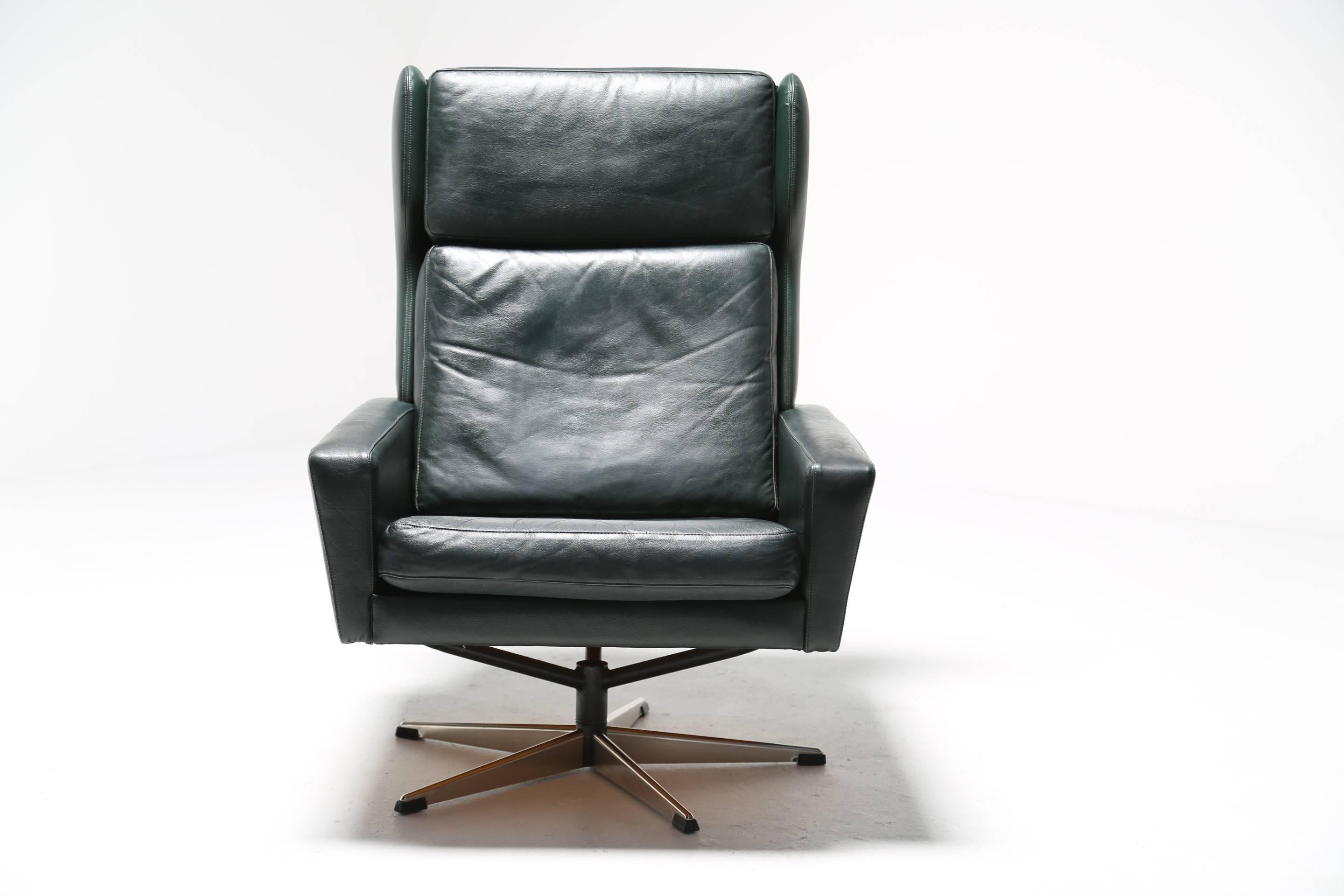 A robust and fabulously comfortable Danish Mid-Century swivel chair designed by Georg Thams for Vejen Polstermøbelfabrik in the 1960s. This chair rests on a polished chrome five star base and is upholstered in it's original deepest dark green